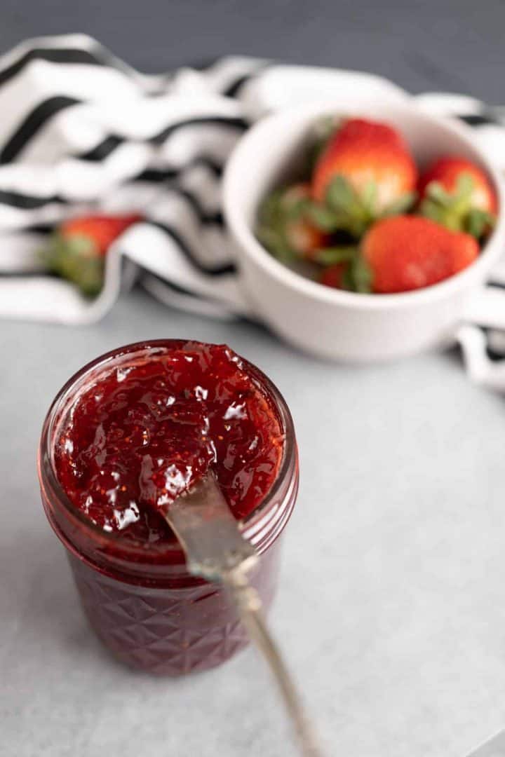 Knife with strawberry jam on it.