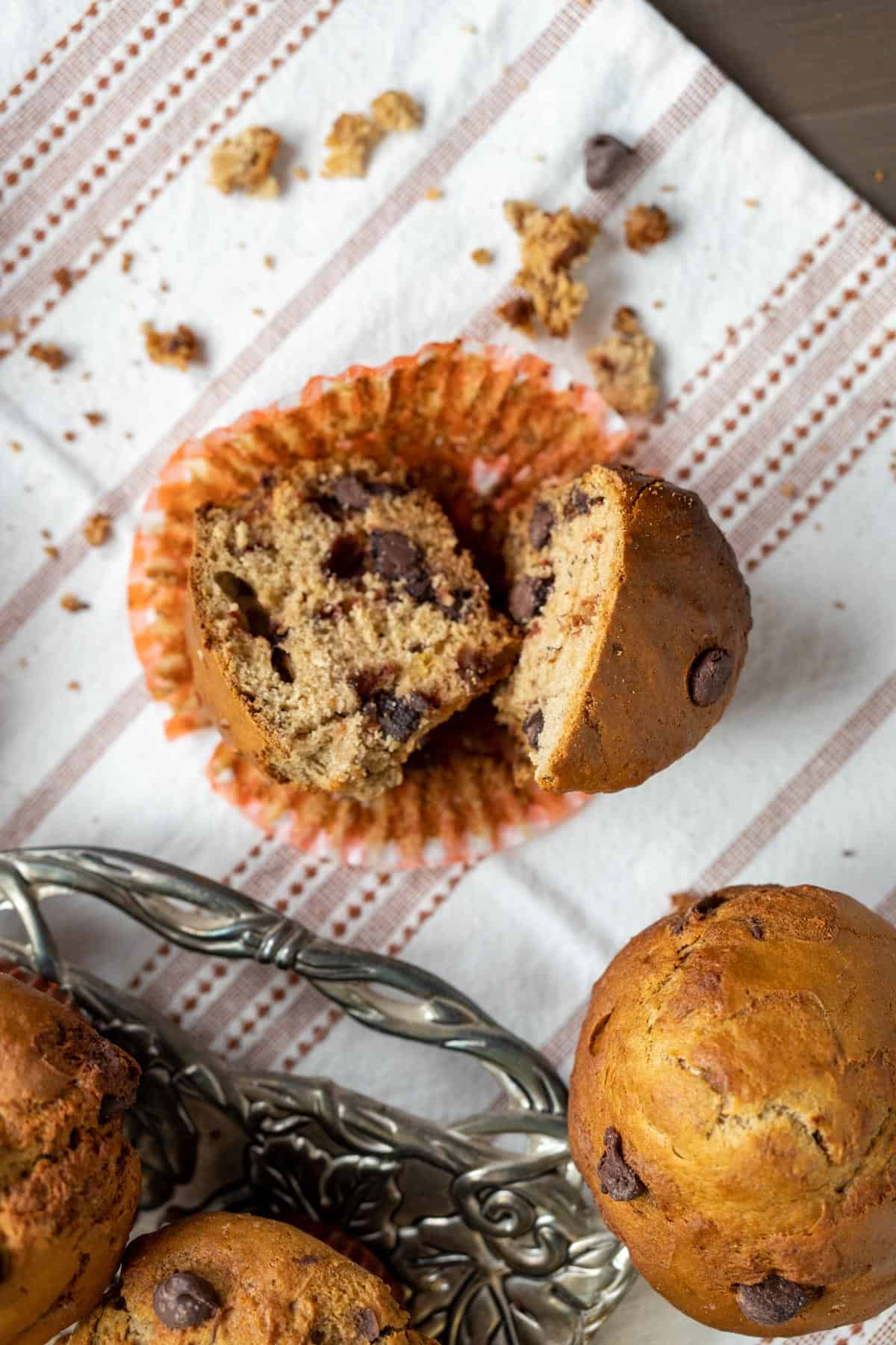 one chocolate chip banana muffin cut in half showcasing the texture of the muffin on white table cloth.