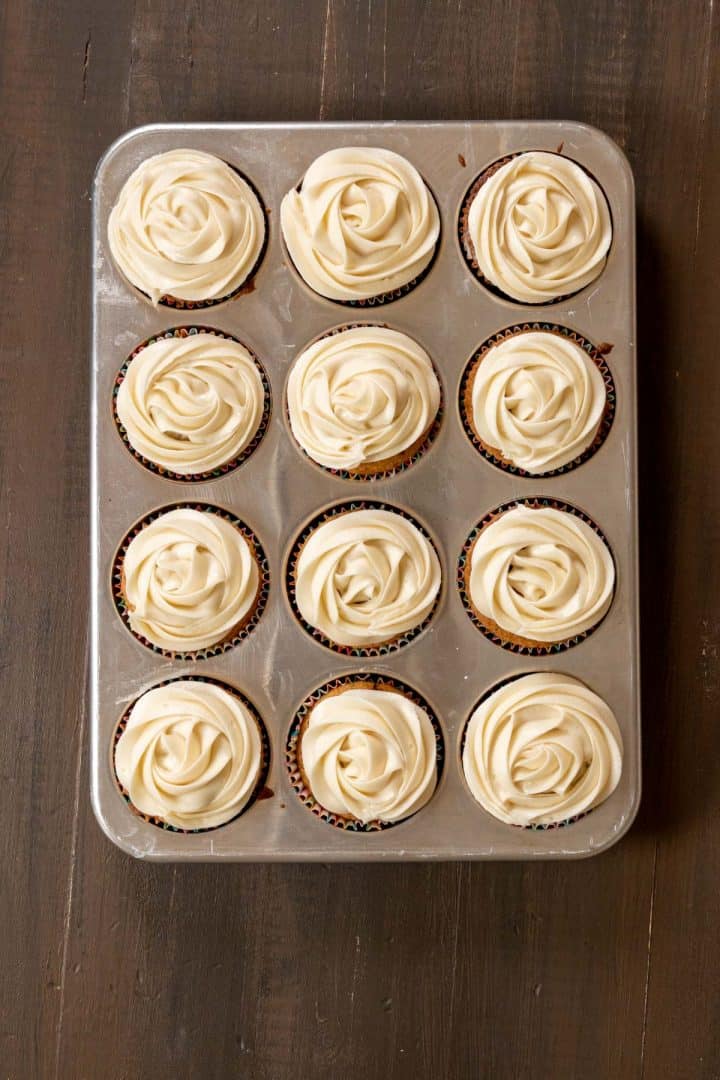 cupcakes in the tray with cream cheese frosting.