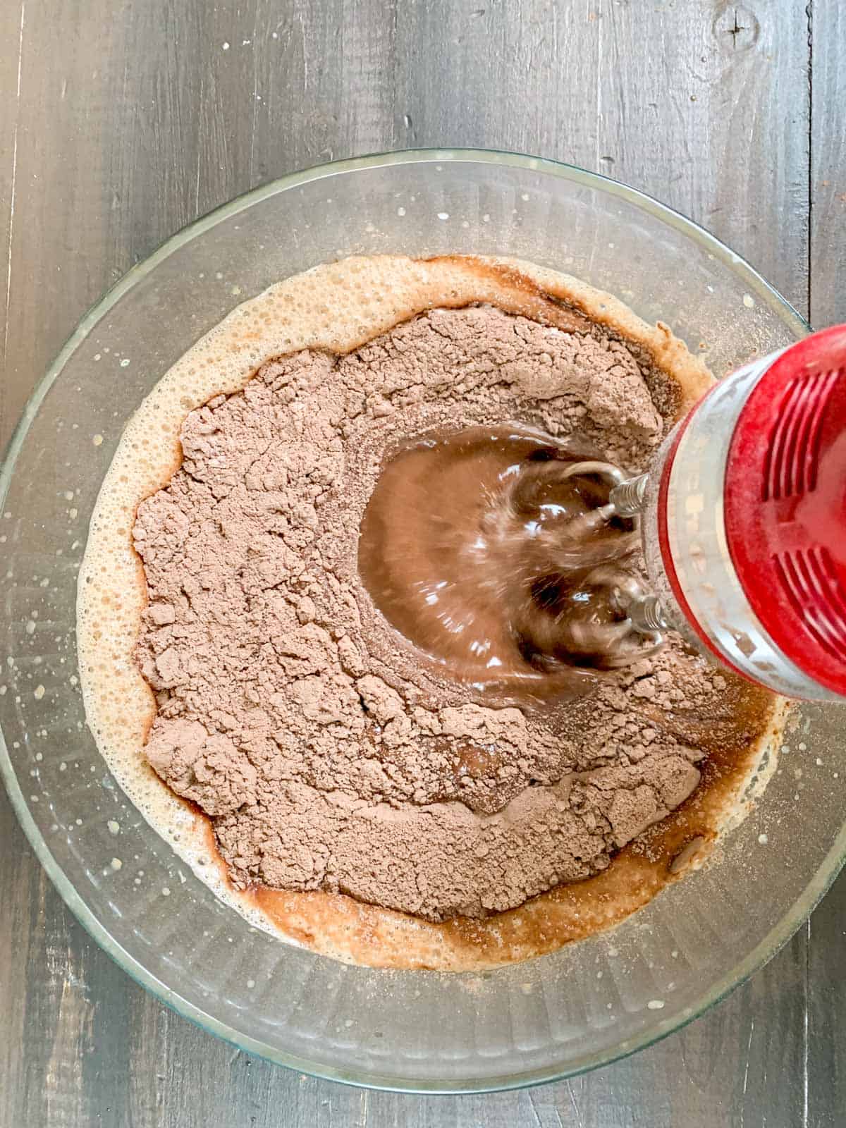 using an electric beater to mix the dry and wet ingredients for the cake.