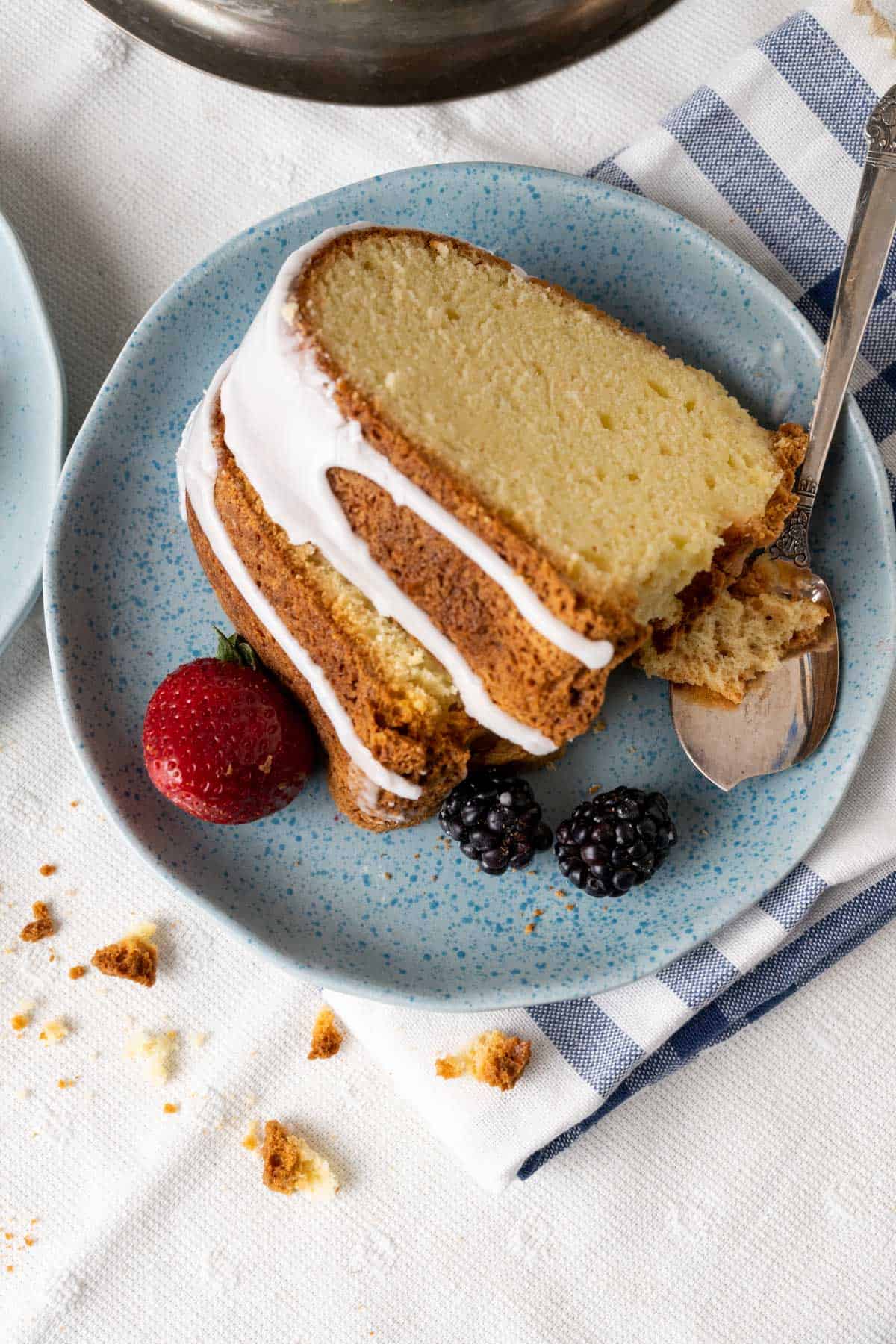 Slices of old-fashioned sour cream cake with berries in blue plate.