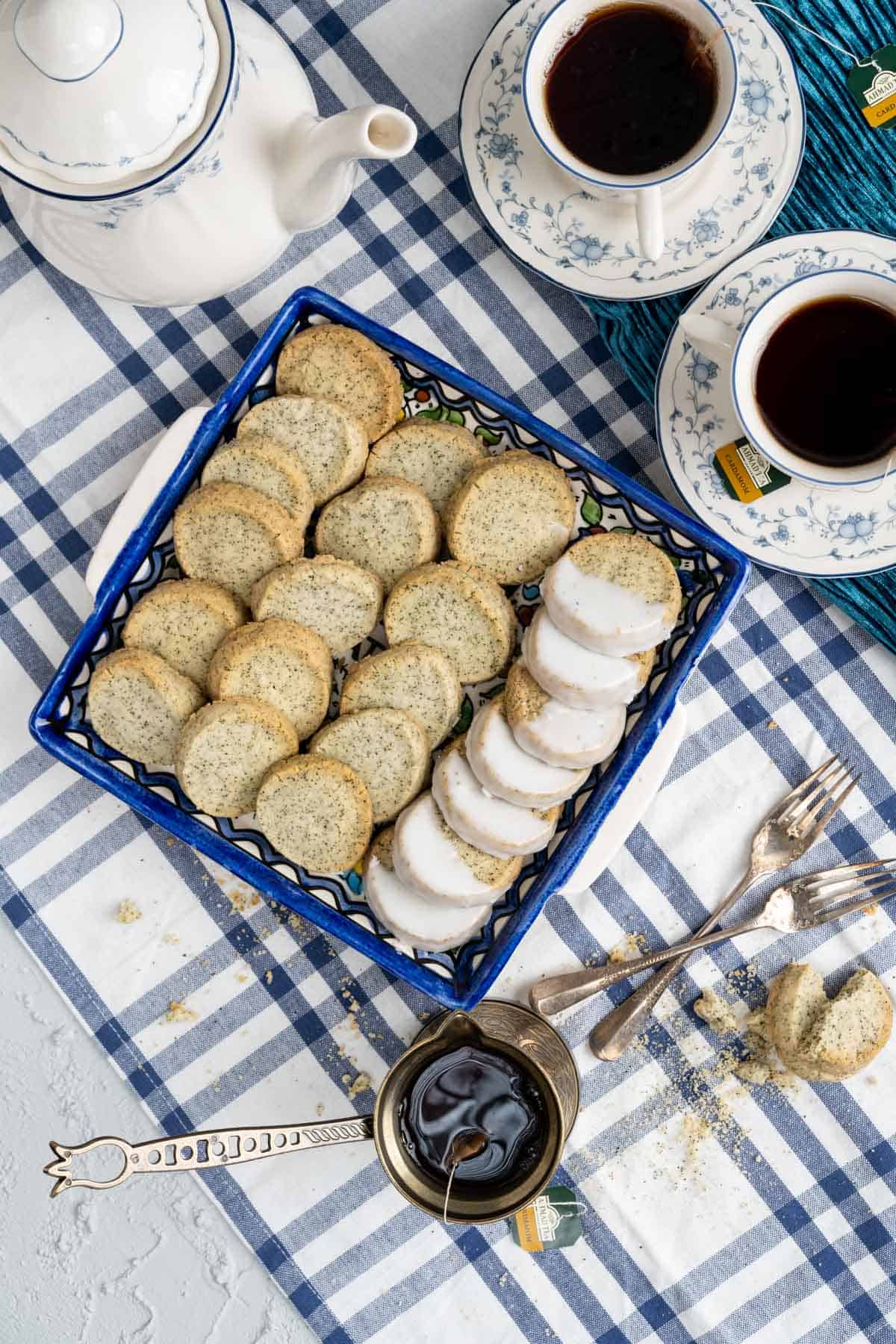 over the head shot of the earl grey shortbread cookies with tea cups and cookies in the deep blue dish.