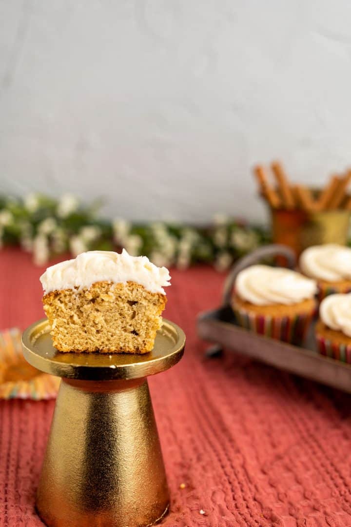 half cut cinnamon cupcake placed on a golden stand showcasing the texture. 