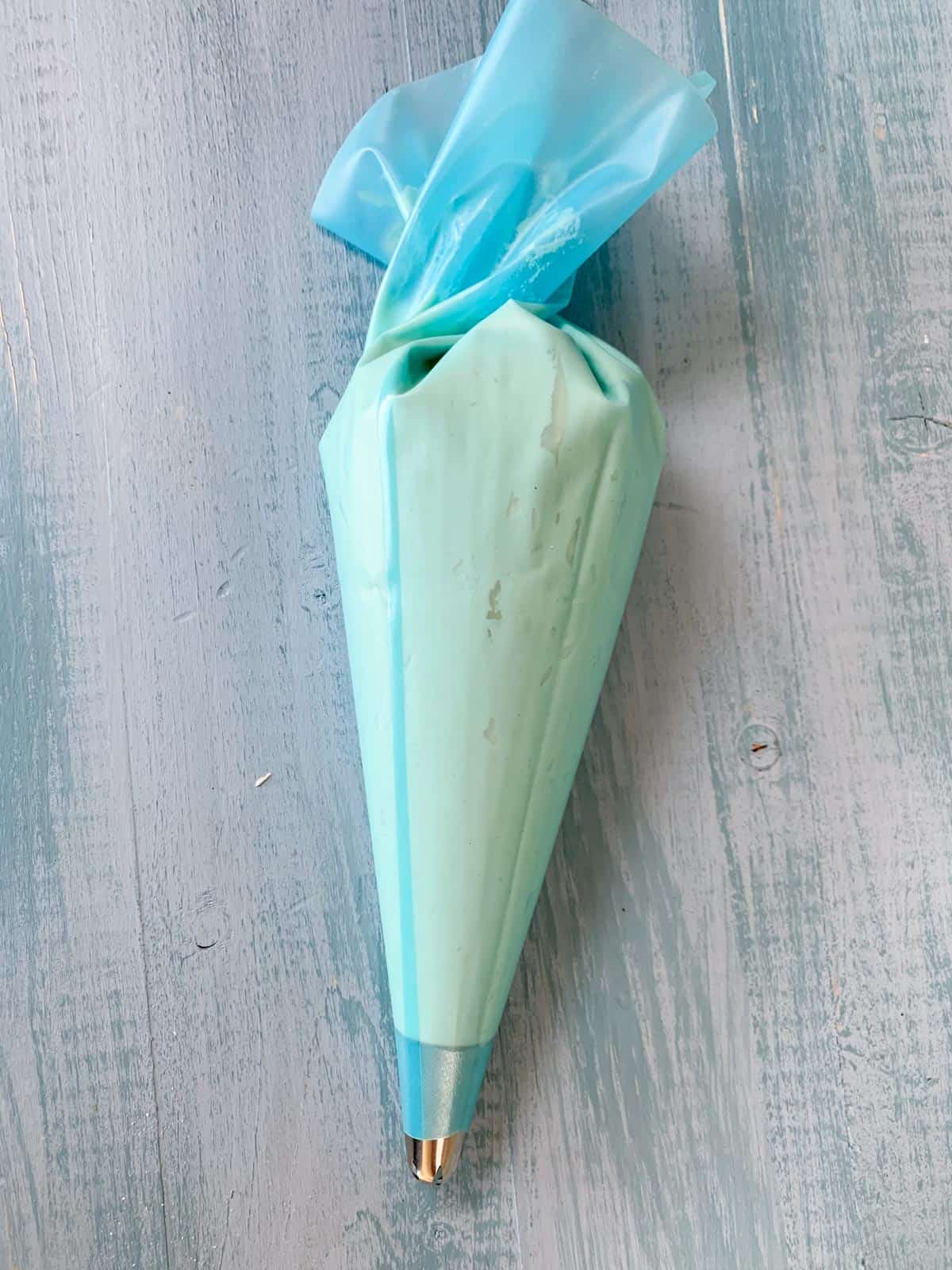 butter frosting in the piping bag laying on the blue table.