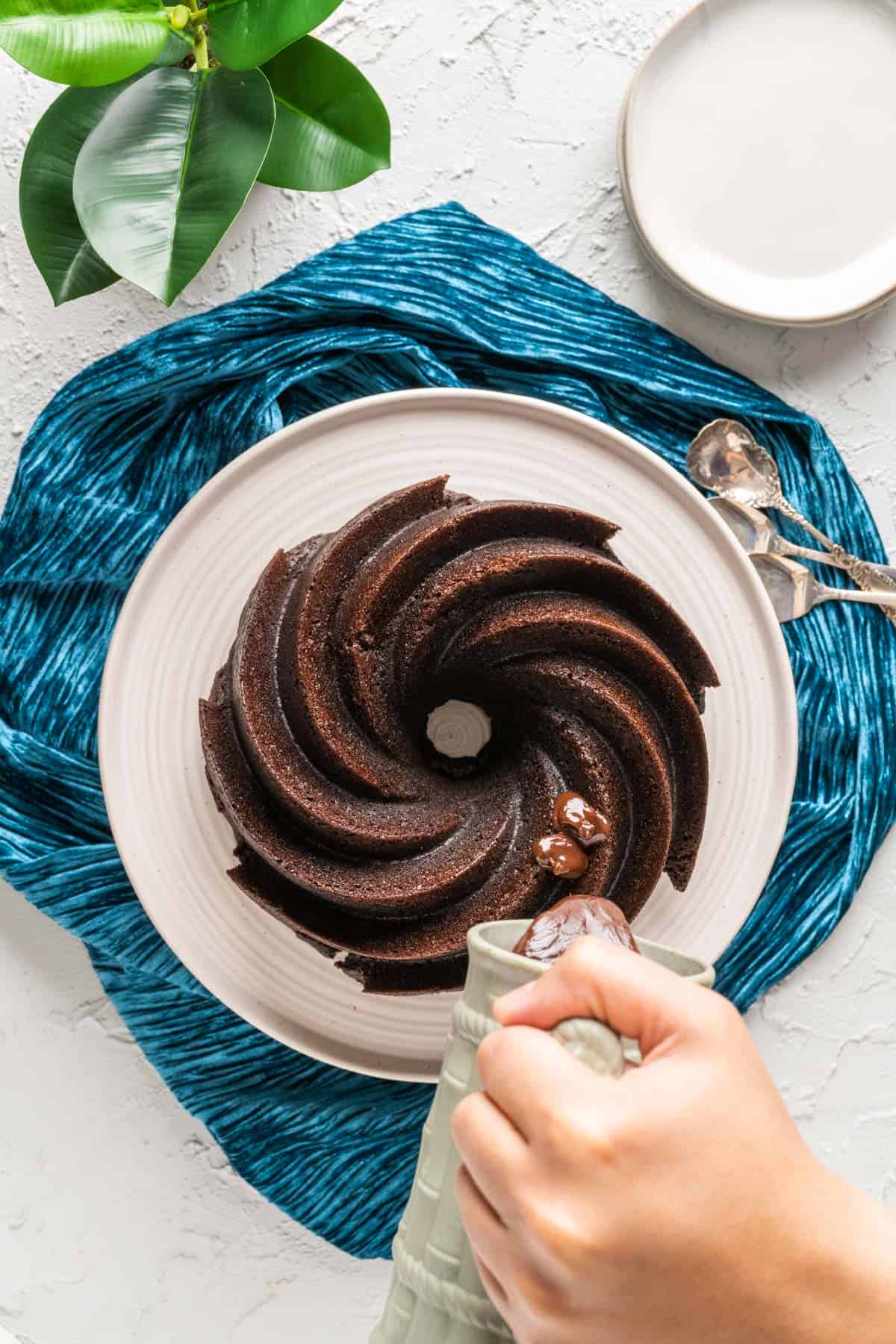 pouring chocolate ganache over the cooled cake.