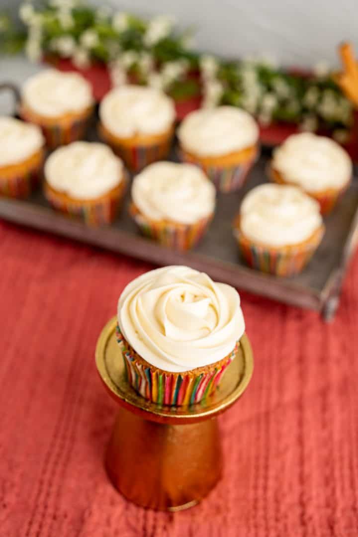 single cinnamon cupcake with silver tray in the backdrop.