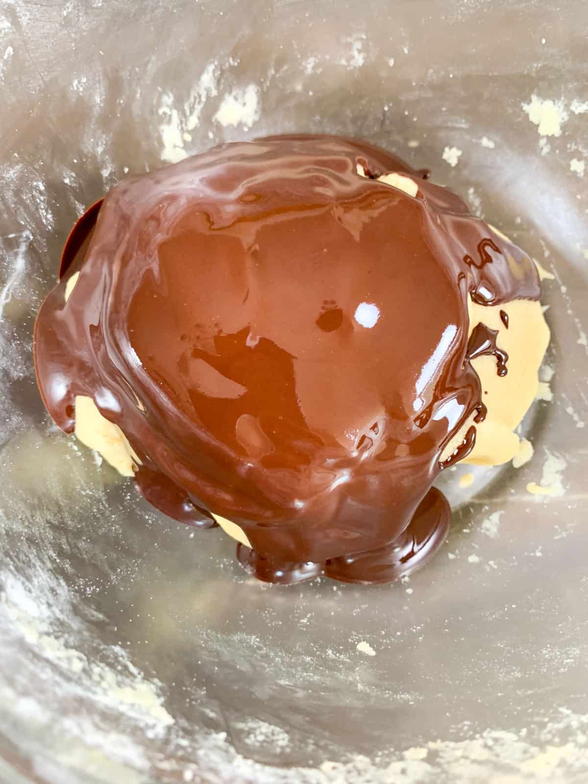 melted chocolate poured over the half pinwheel cookie dough in a bowl.