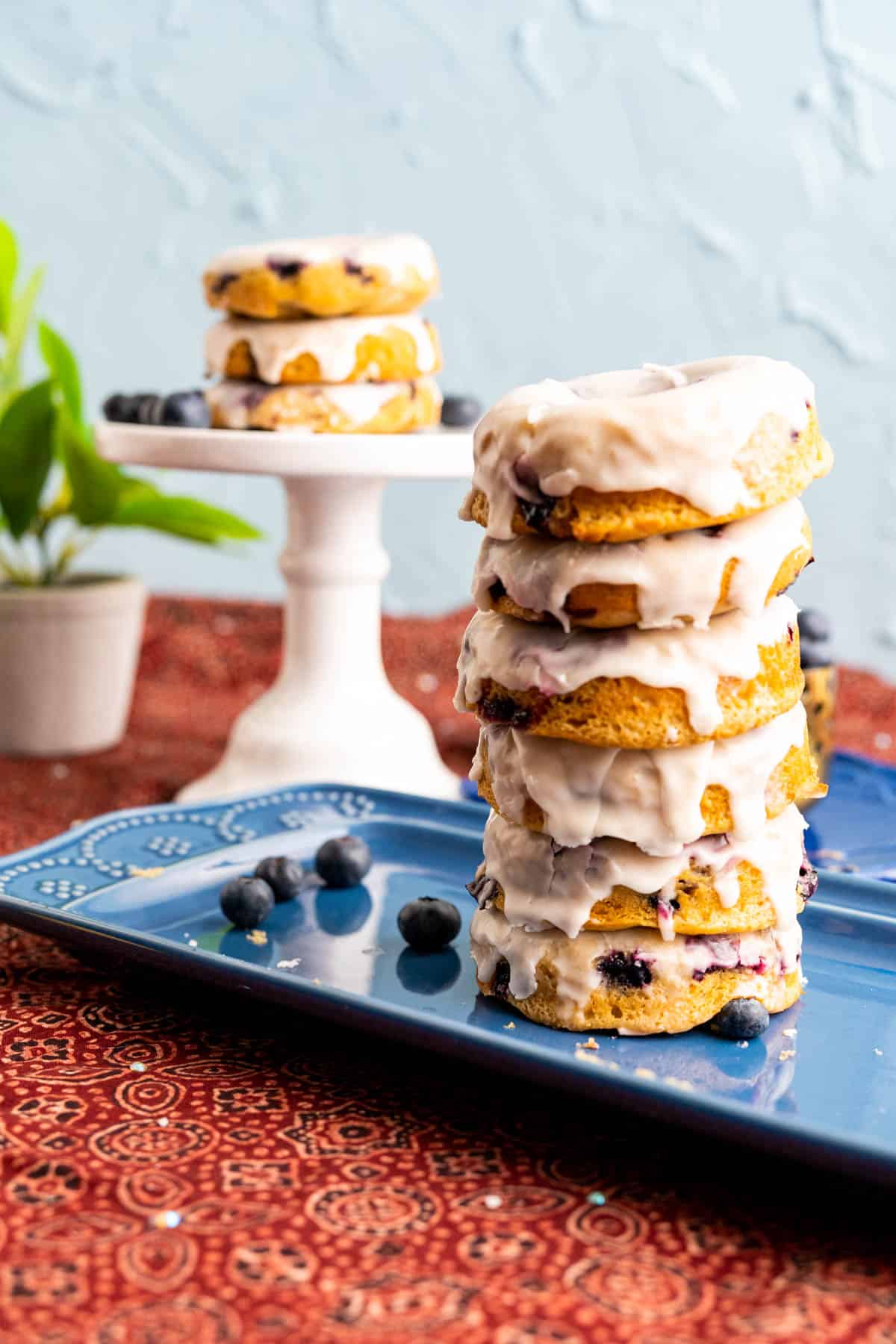 piles of baked blueberry donuts on each other in a navy blue square plate.