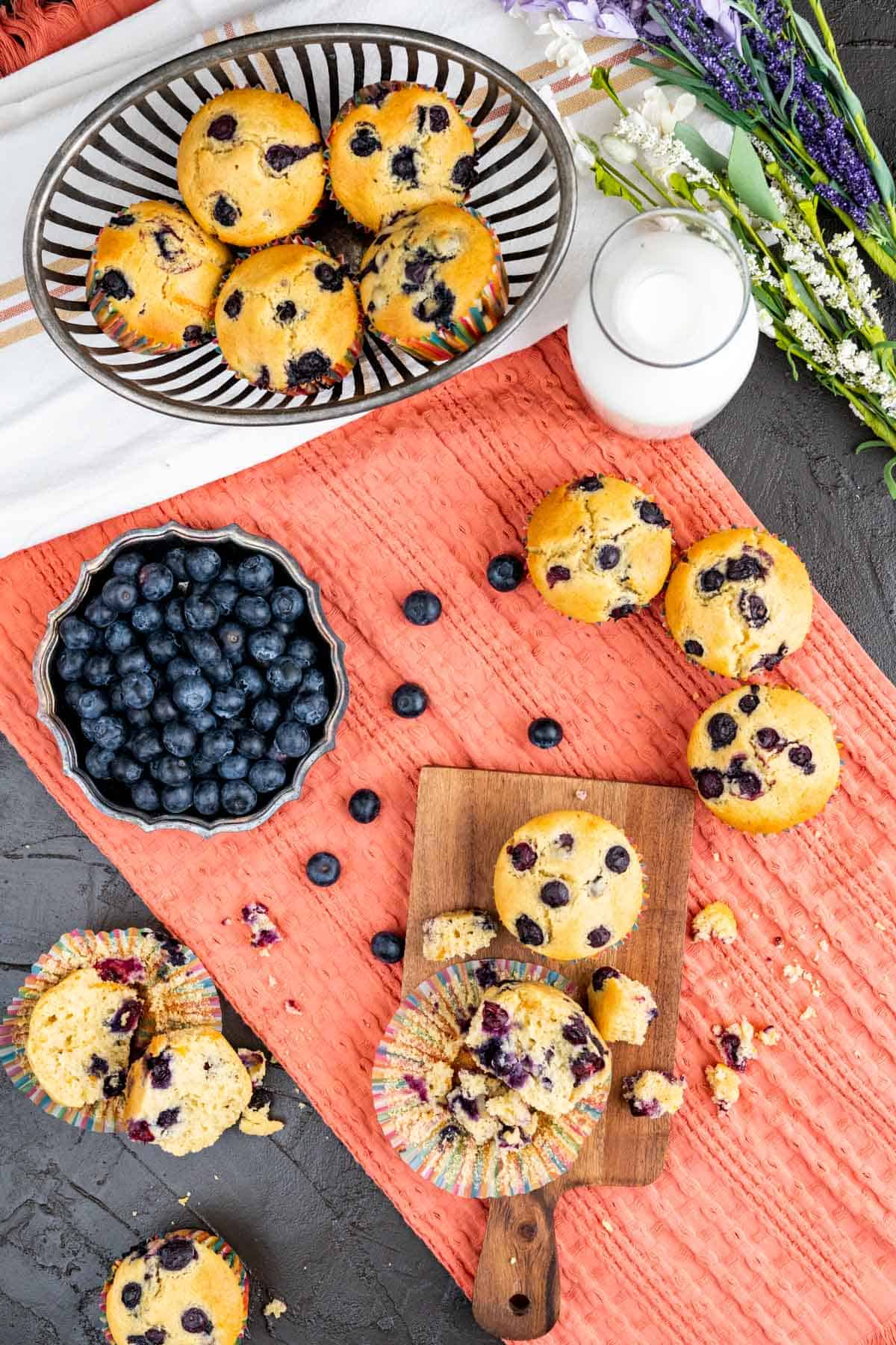 old-fashioned blueberry muffins scattered on the table over the head shot.