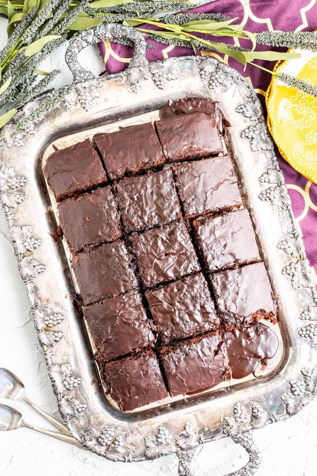 overhead shot of coca cola cake in an antique silver tray with flowers around.