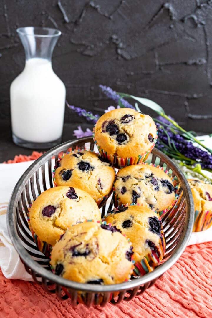 six muffins in the basket with milk bottle in the backdrop.