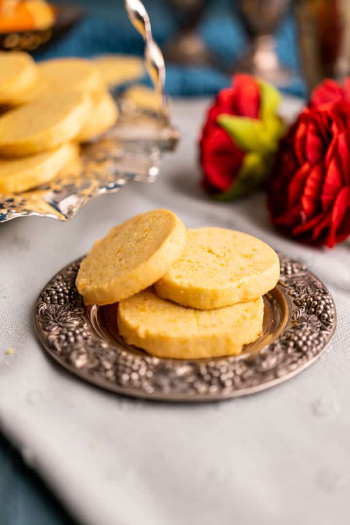 Three orange cookies sitting on a silver small plate.