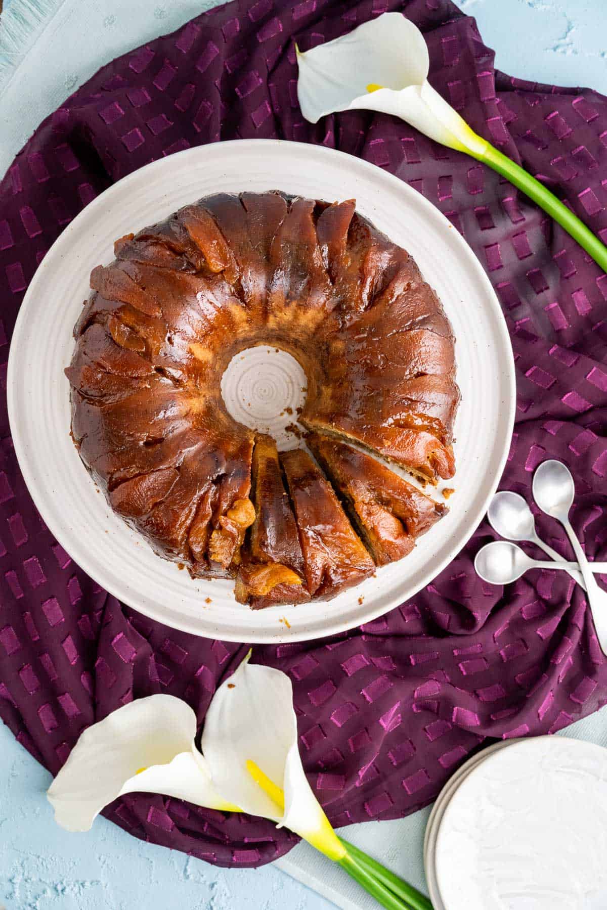 overhead shot of peach cobbler pound cake in a white cake tray with lily flowers around. 