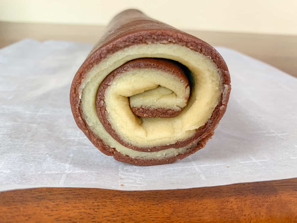 side shot of the pinwheel cookies log showcasing vanilla and chocolate swirls.