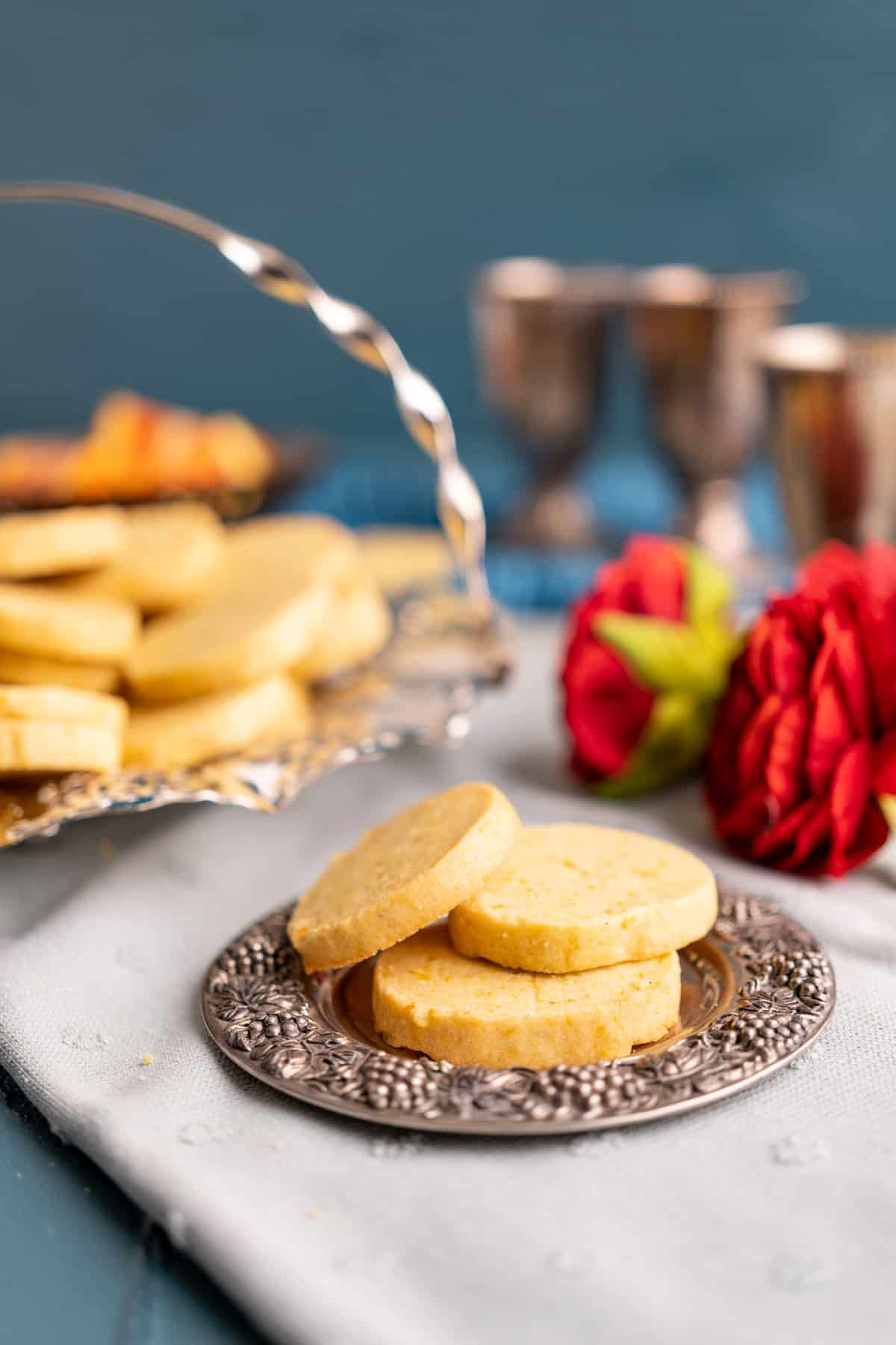 Three orange cookies placed on a small cute silver plate.