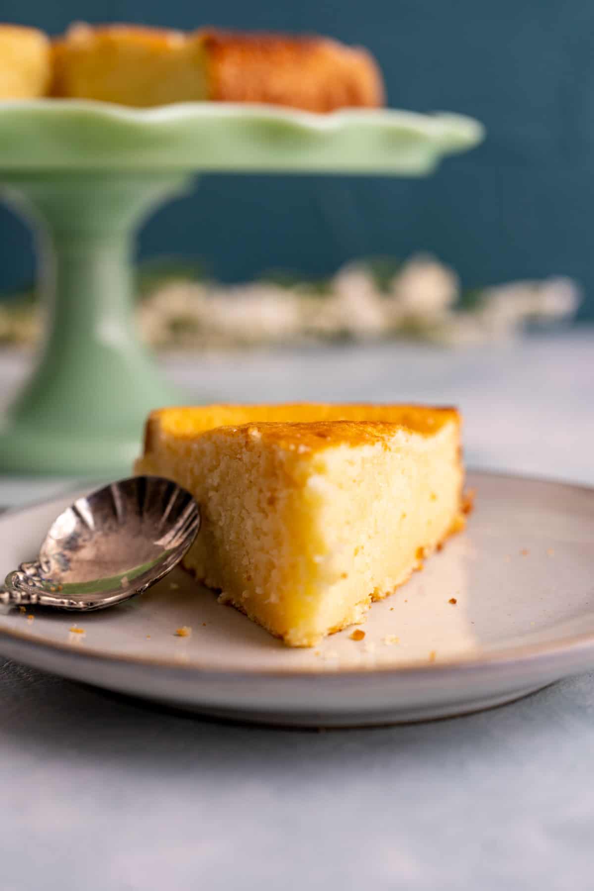 slice of california pizza kitchen butter cake with silver spoon in a small white plate.