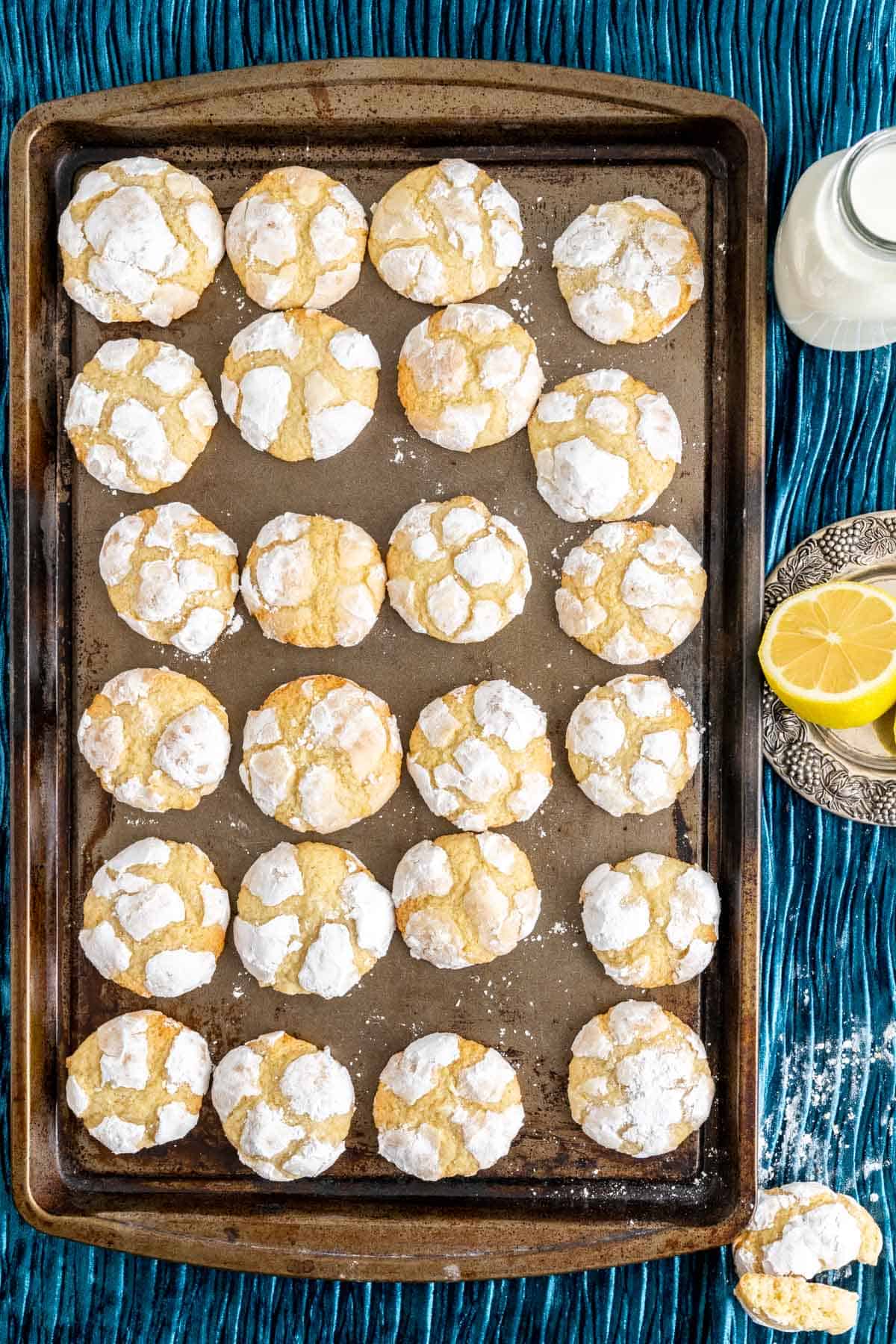 lemon crinkled cookies sitting in an antique silver tray along with a milk bottle and a lemon.