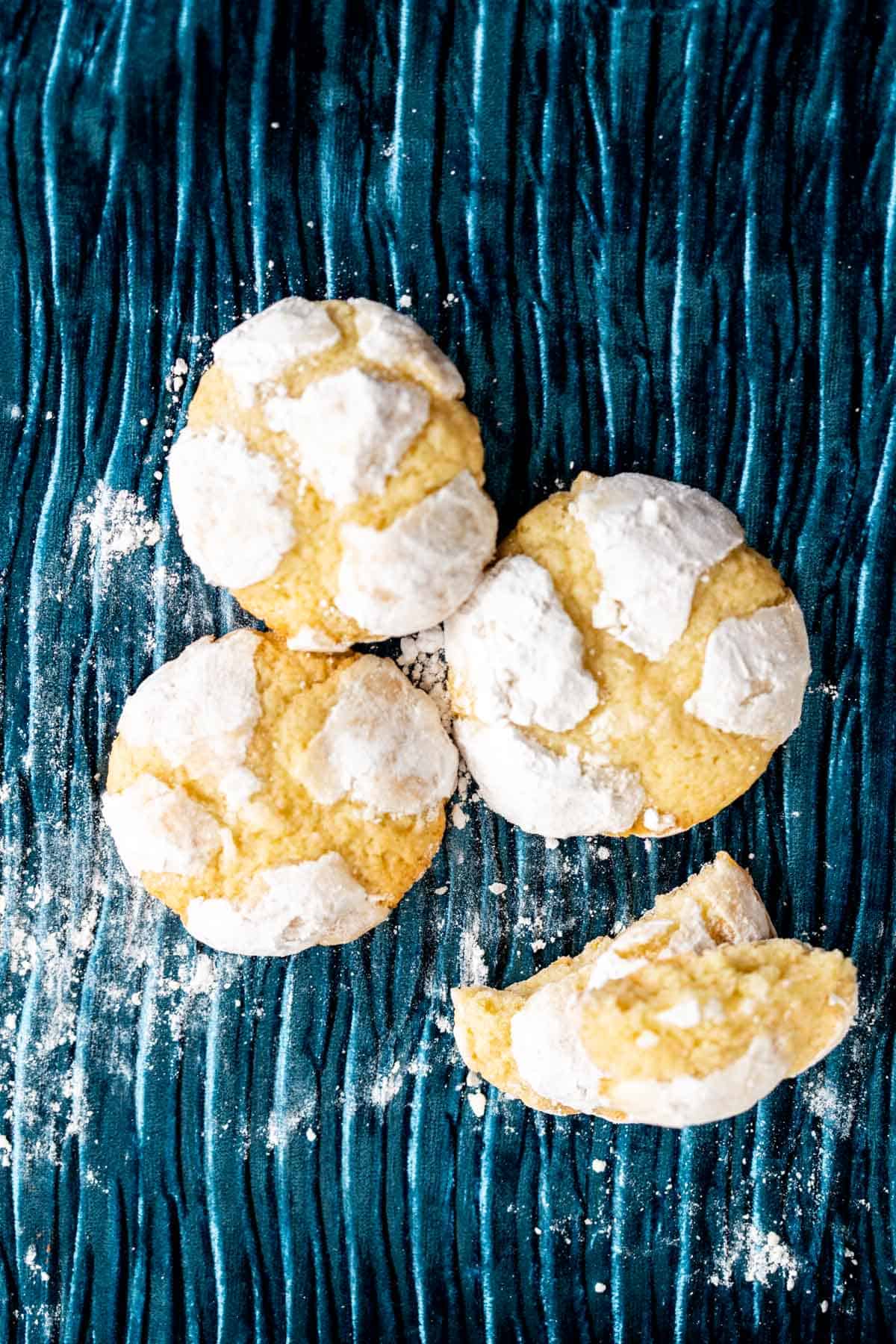 three lemon cookies placed with each other on a crinkled blue cloth.