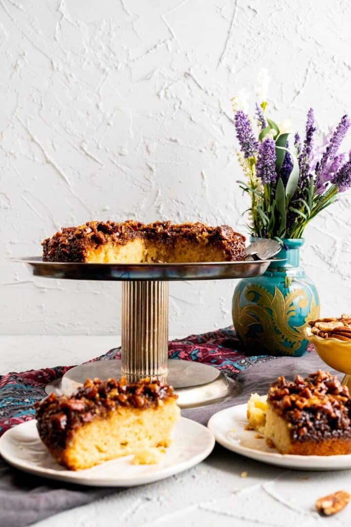 pecan upside down cake on the cake plate and cake slices on the white plates.