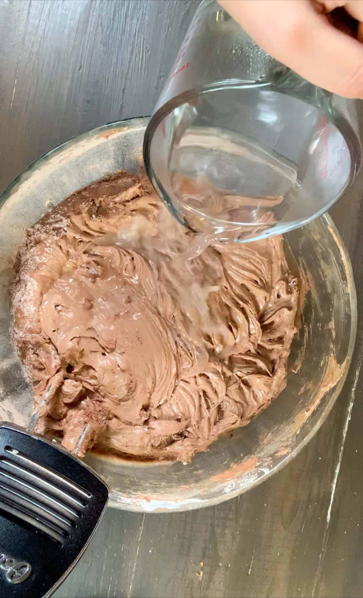 adding the boiling hot water to the chocolate sour cream pound cake batter.