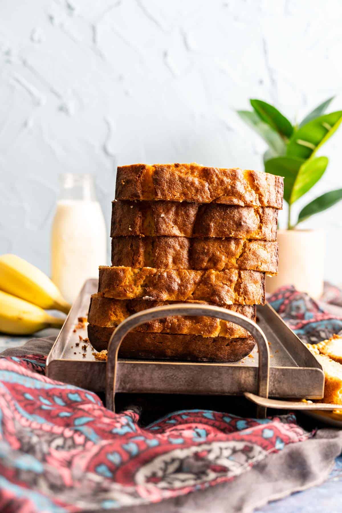 slices of 4-ingredient banana bread sitting on a gray plate with a milk bottle in the backdrop.