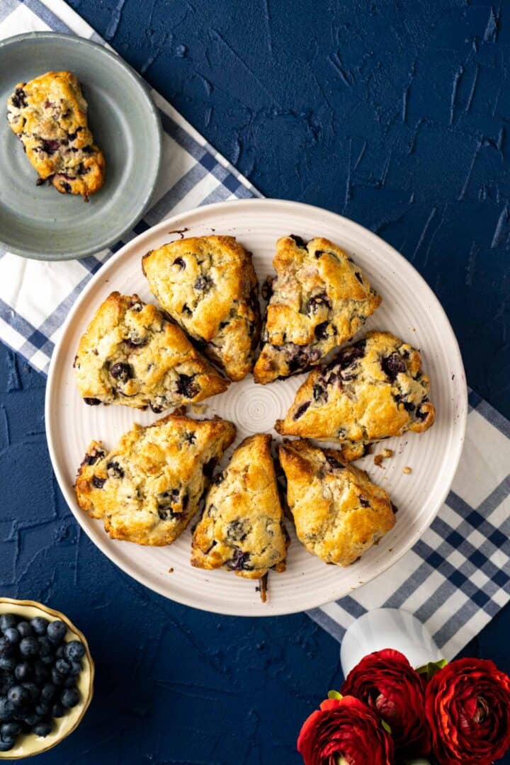 overhead shot of the starbucks blueberry scones placed in a white cake plate over blue and white table cloth.