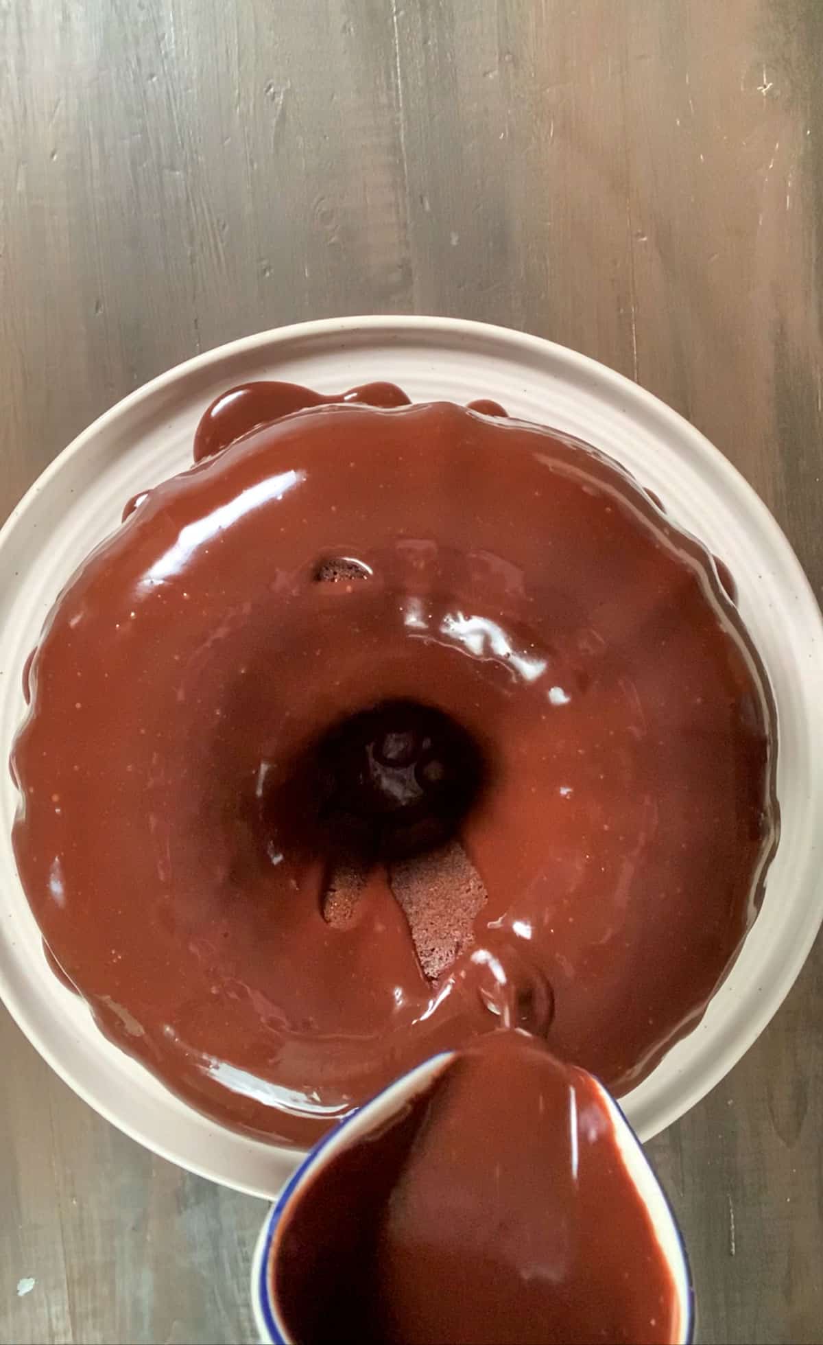 pouring chocolate ganache over the chocolate sour cream pound cake.