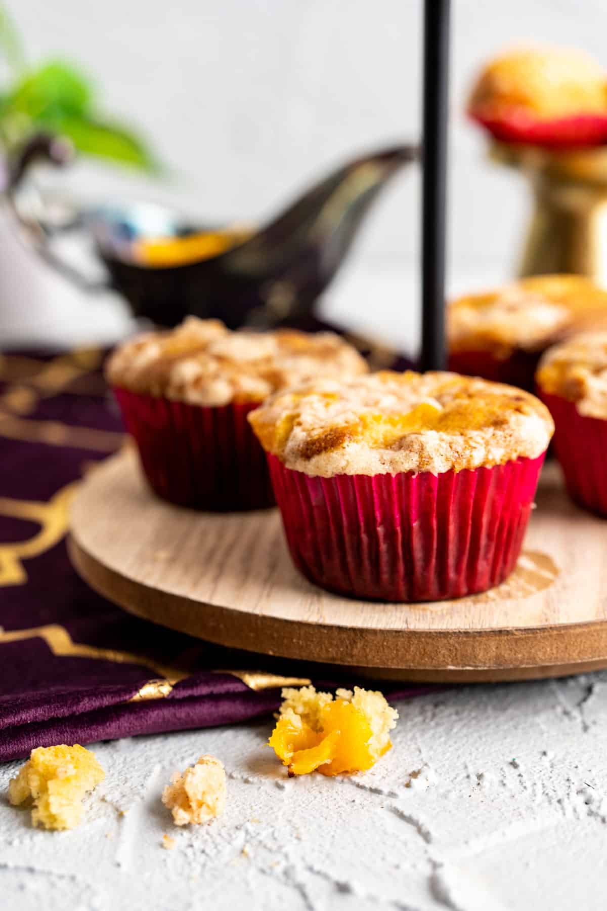 peach cobbler muffins sitting on a muffin stand in red cupcake liners.