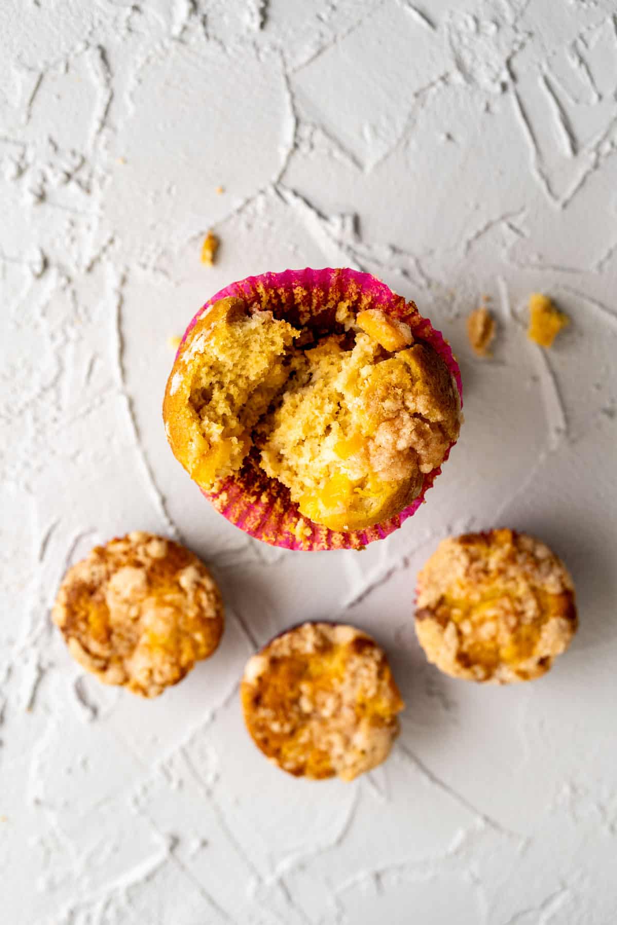 overhead shot of four peach cobbler muffins on the table showcasing the texture.