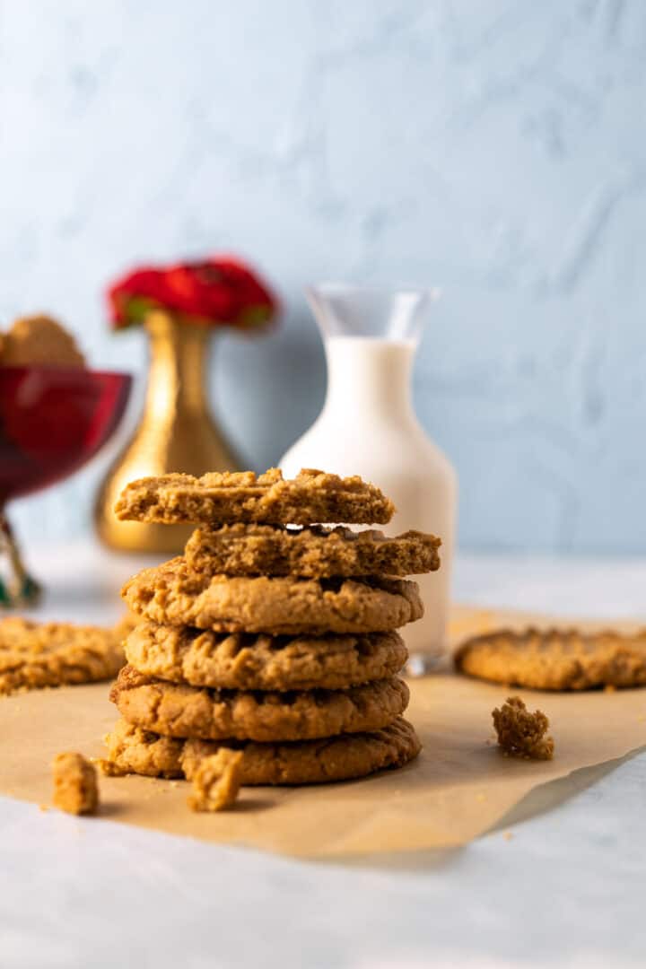 almond flour peanut butter cookies stacked on each other with milk bottle in the back.