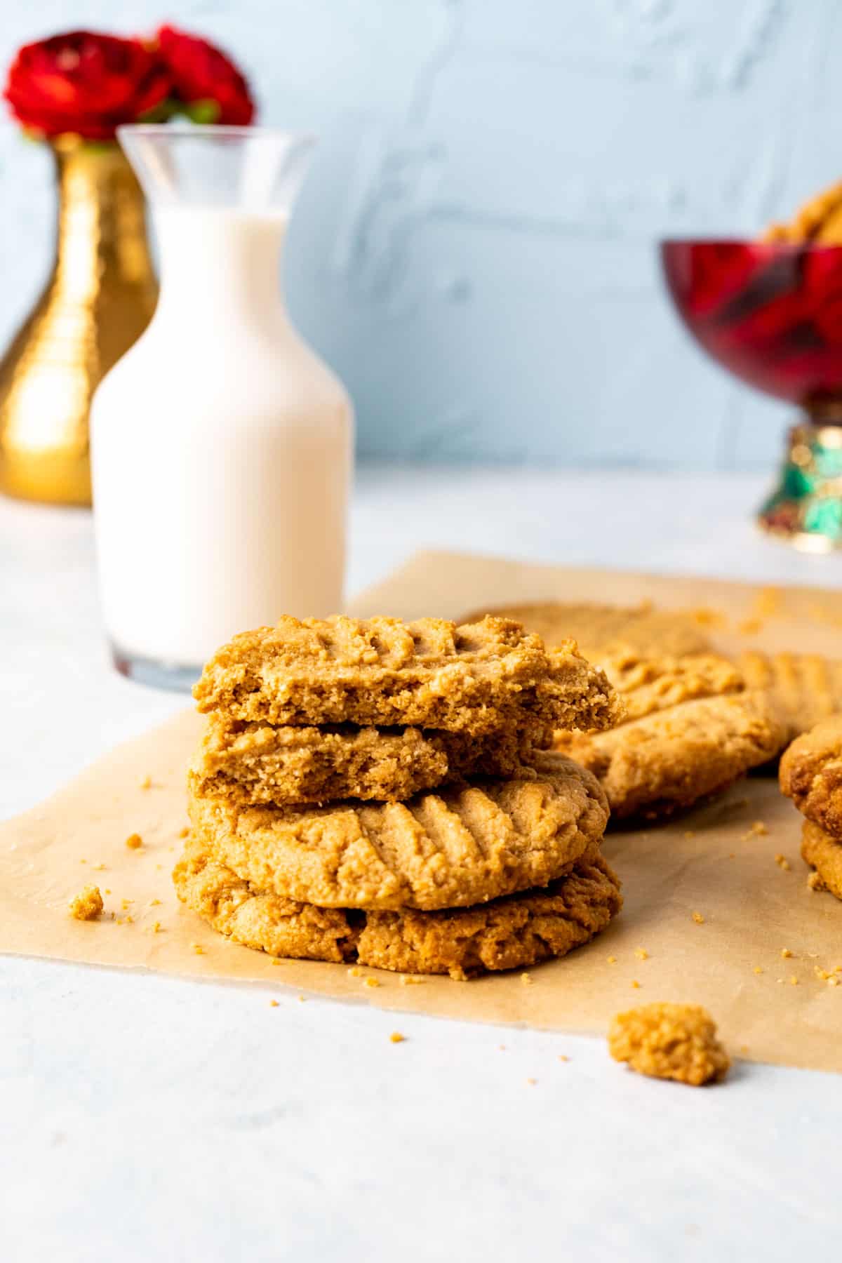 Three almond flour peanut butter cookies stacked on each other with milk bottle in the backdrop.