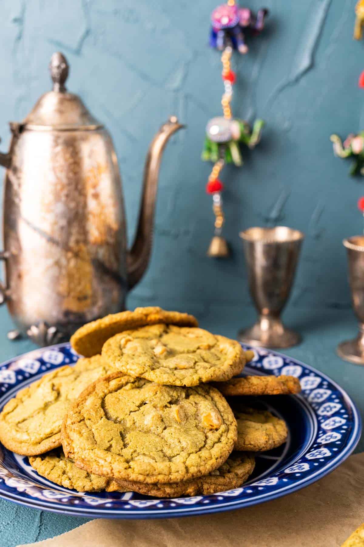 an antique blue and white plate filled with matcha cookies with silver tea pot and cups in the backdrop.