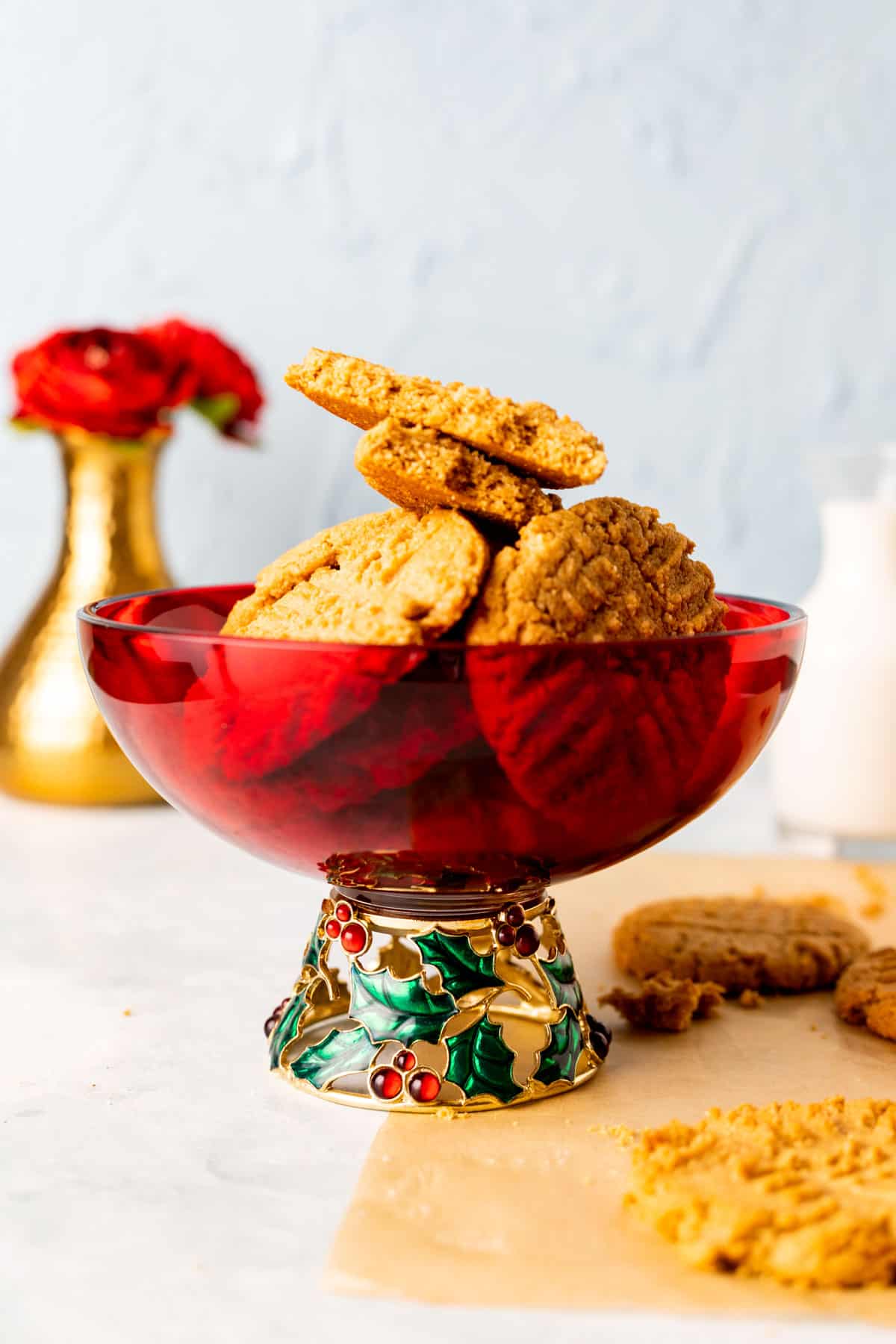 Almond flour peanut butter cookies placed in a decorative red bowl with a golden vase in the backdrop.