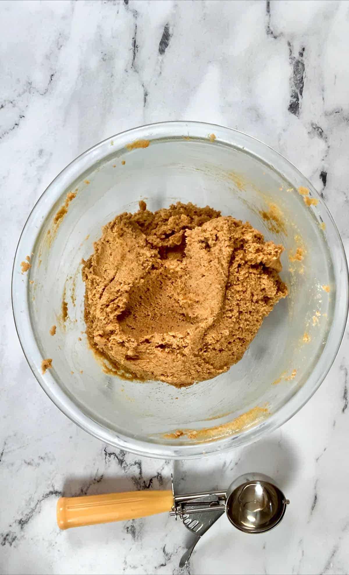 Peanut butter cookies dough with an ice cream scoop on the side.