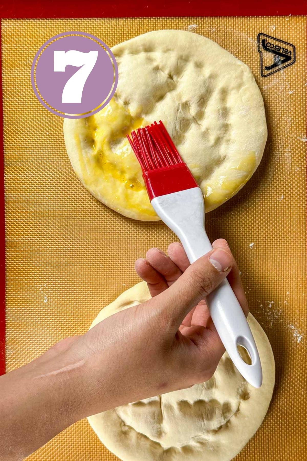 brushing the egg wash on turkish bread loaves before baking.