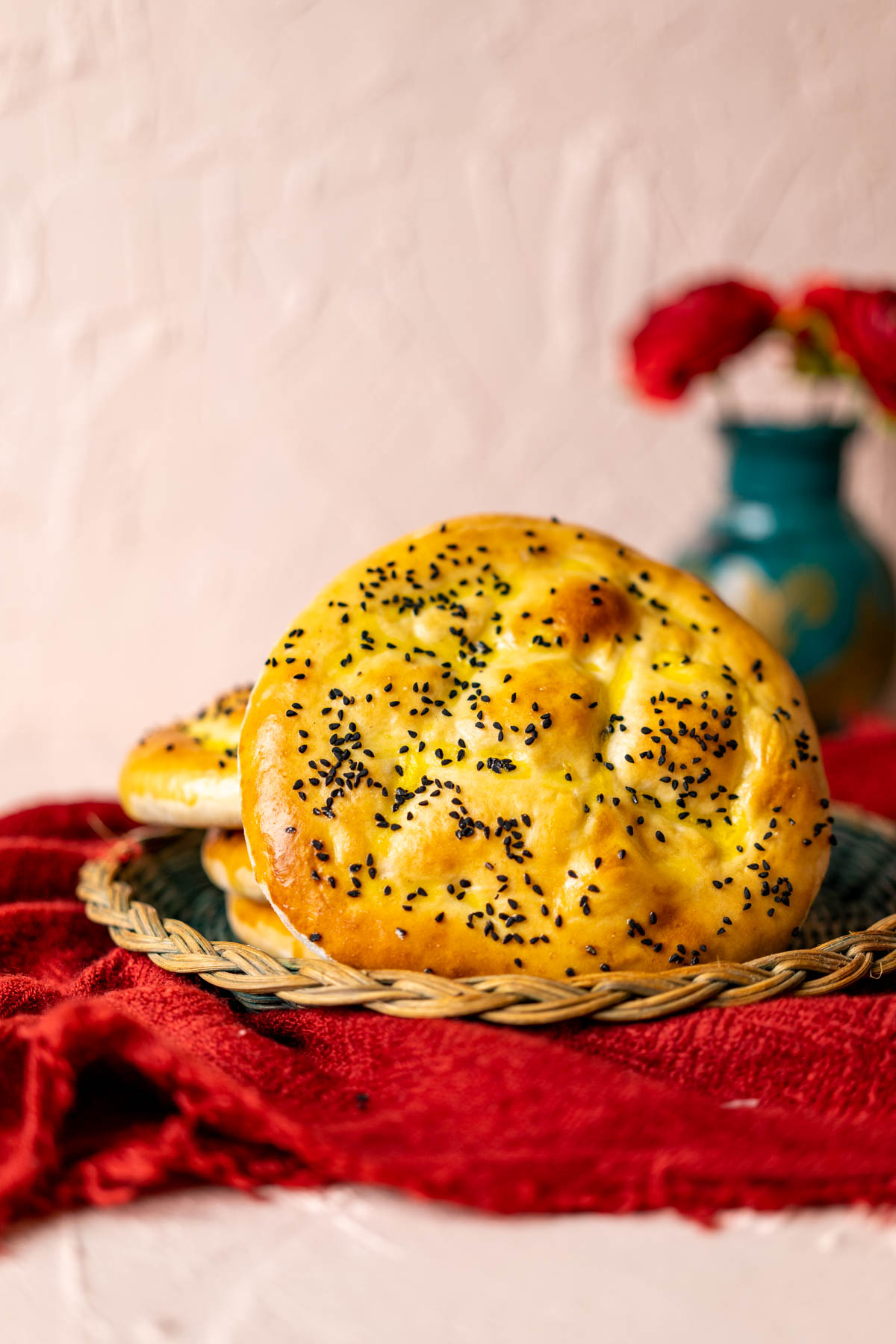 A close shot of whole turkish bread piece with a flower vase in the backdrop.