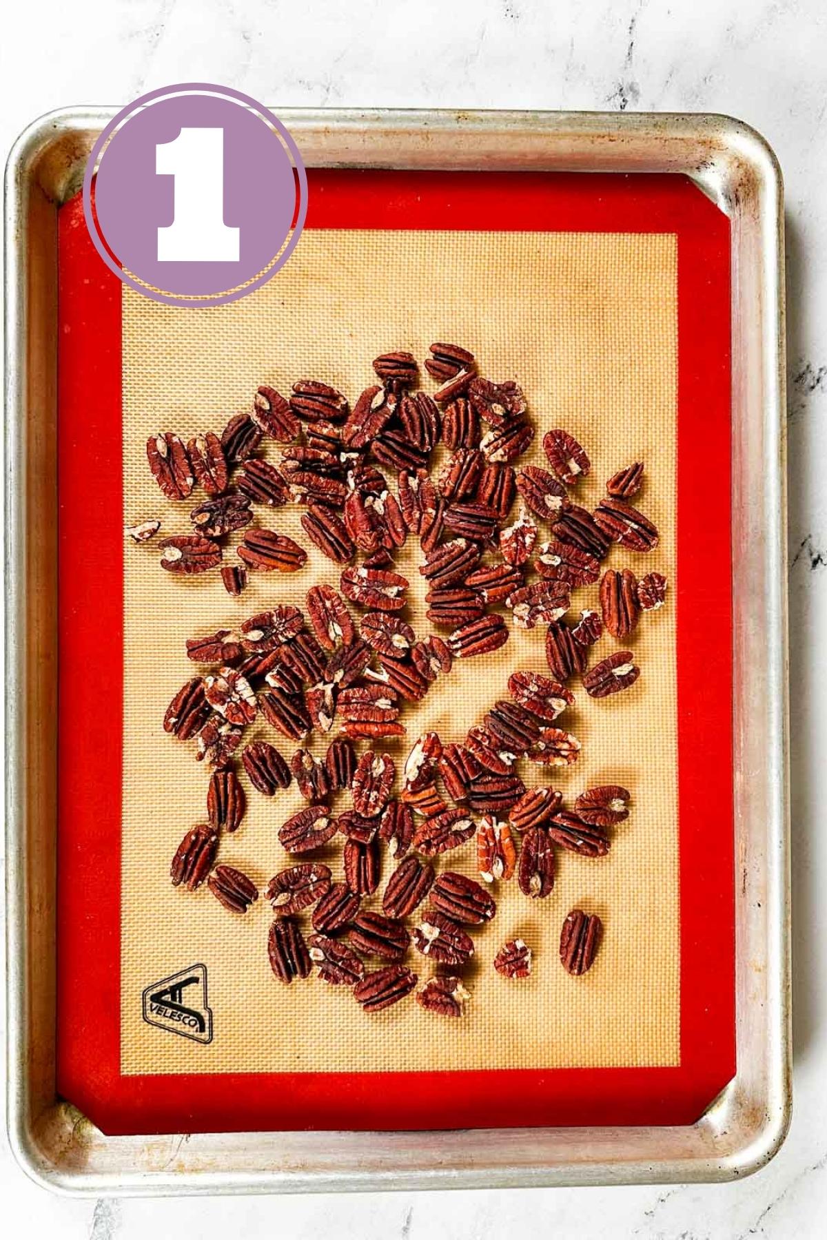 pecans placed on a silicone sheet on a baking tray to prepare the chocolate covered pecans.