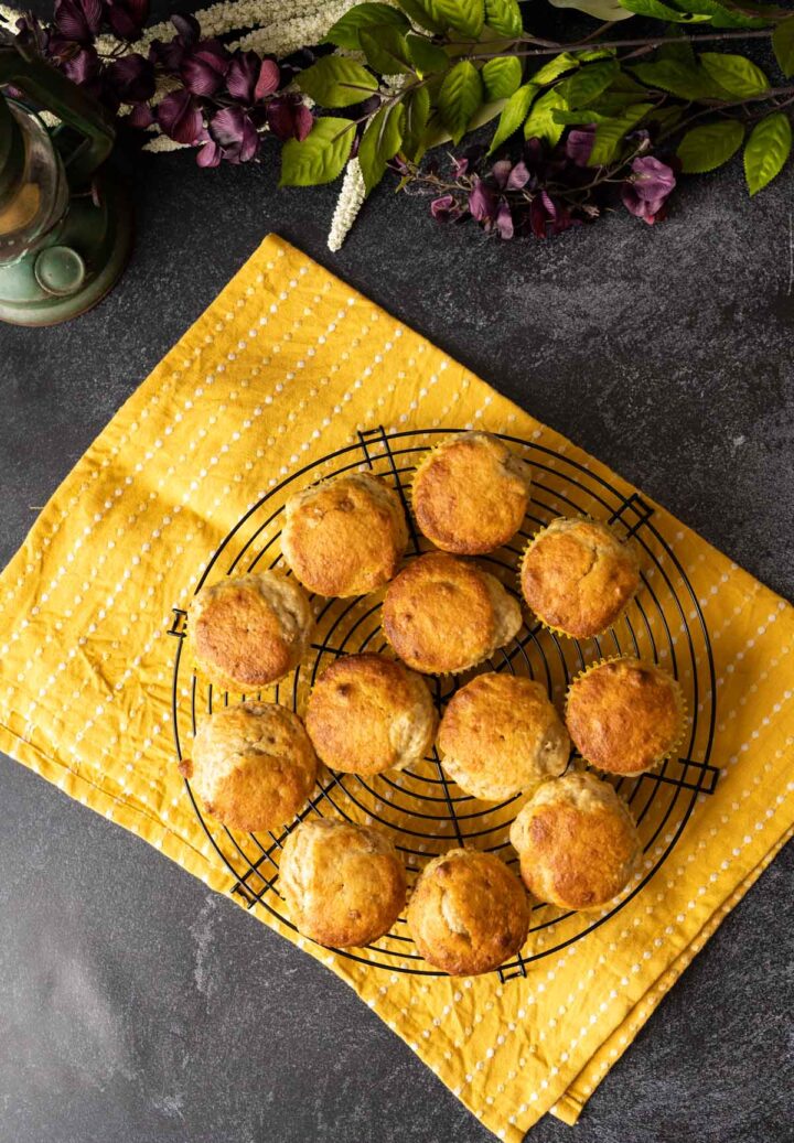 Bisquick banana muffins placed on a black circular wire rack on a black backdrop with yellow table cloth.