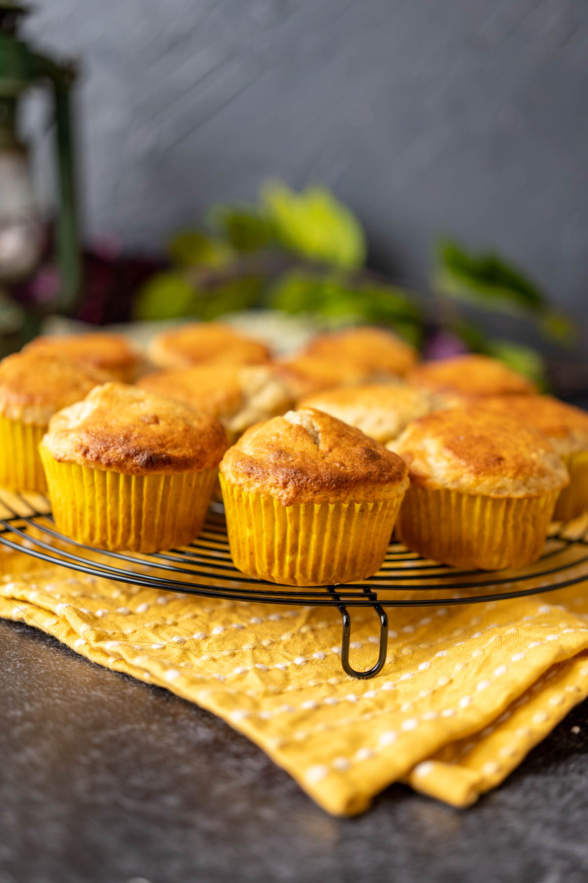 Bisquick banana muffins placed on a black wire rack over yellow table cloth.