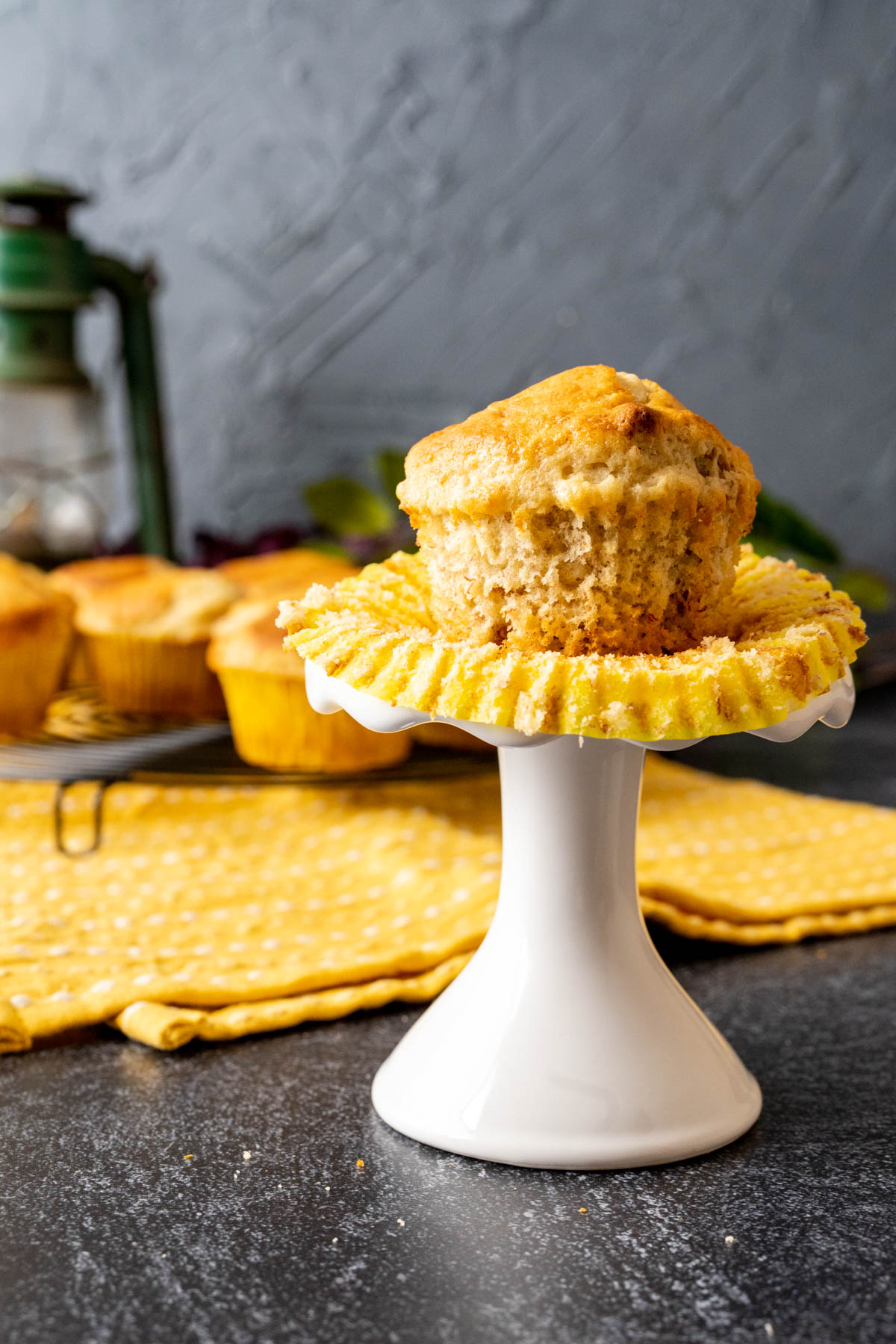 A muffin on a white stand with a lantern in the backdrop.