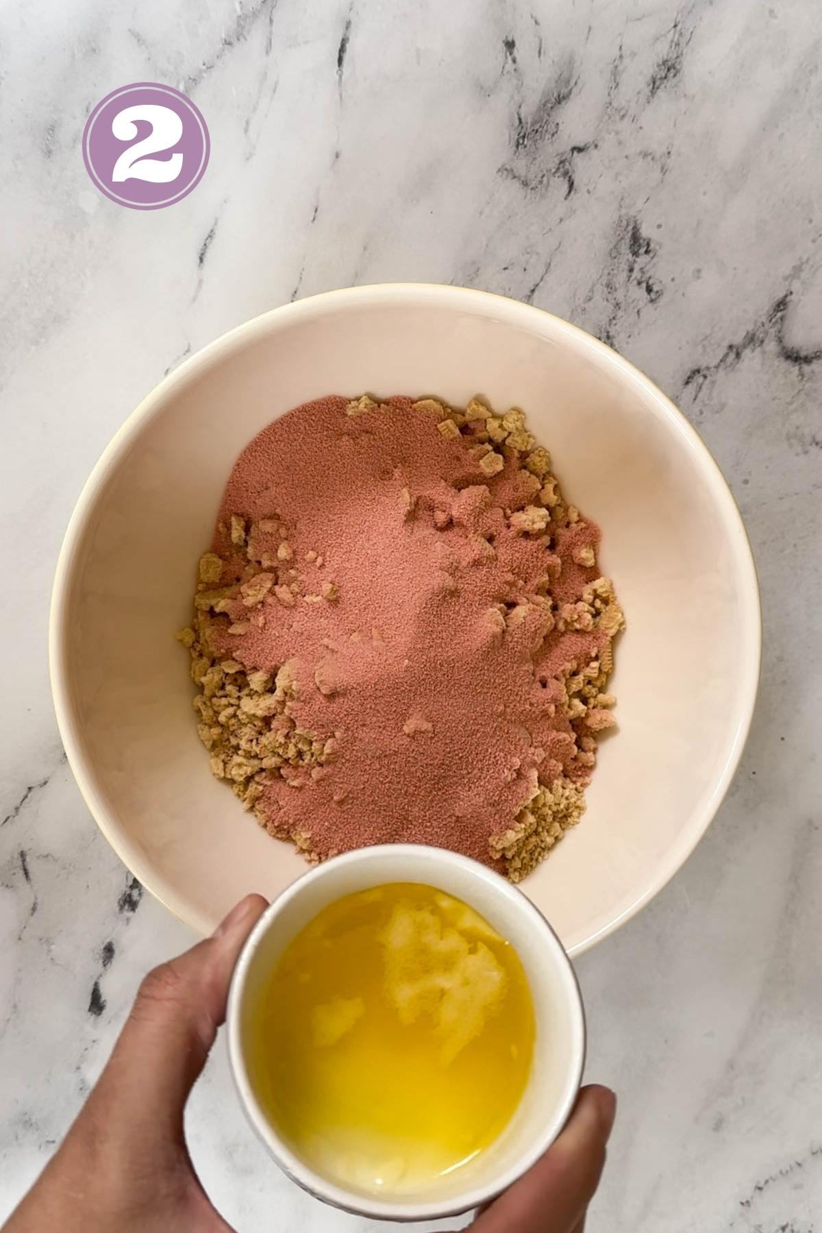 adding the melted butter in a bowl with golden oreos and strawberry Jell-O. 