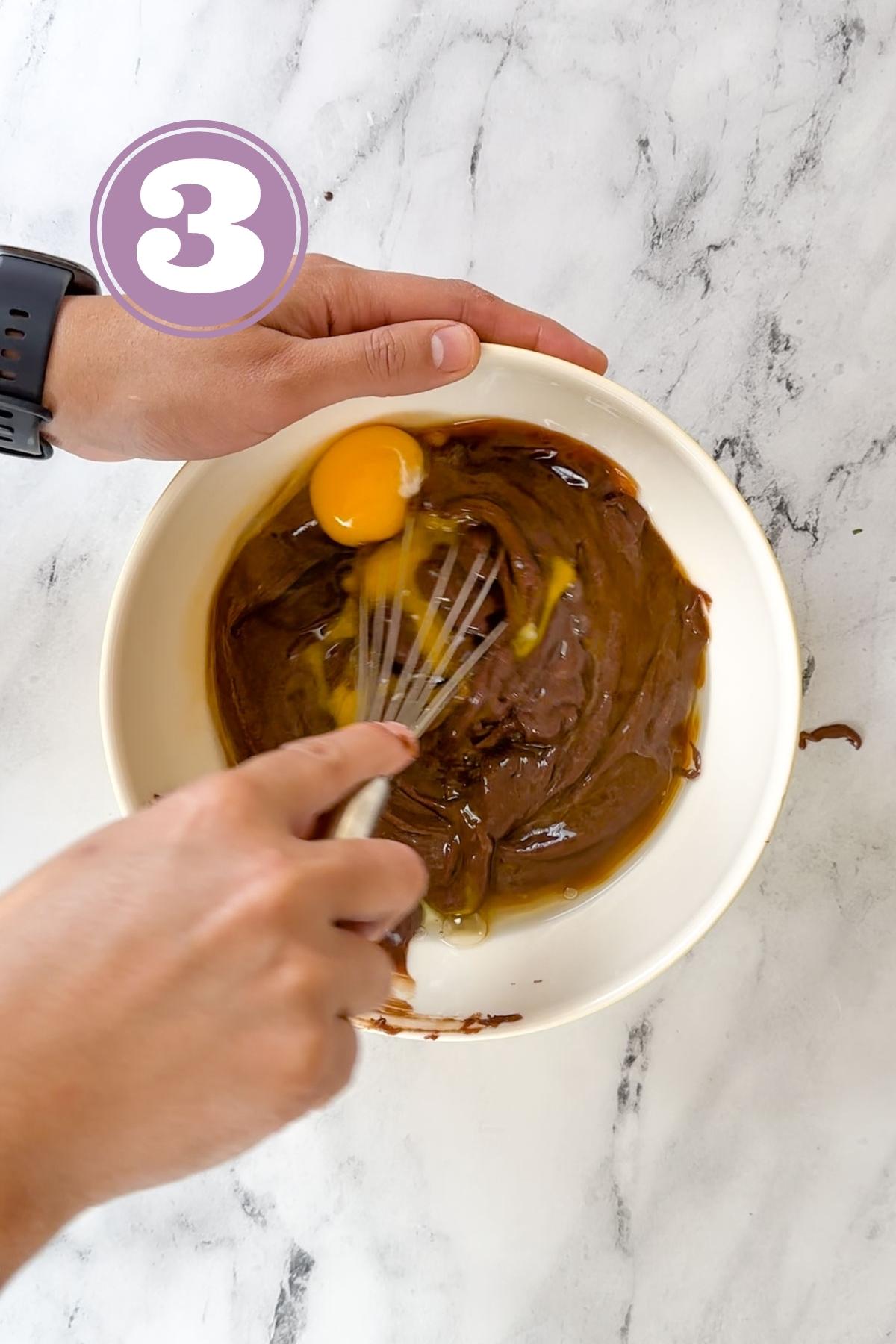 Whisking the eggs and vanilla extract together with chocolate in a medium sized bowl.