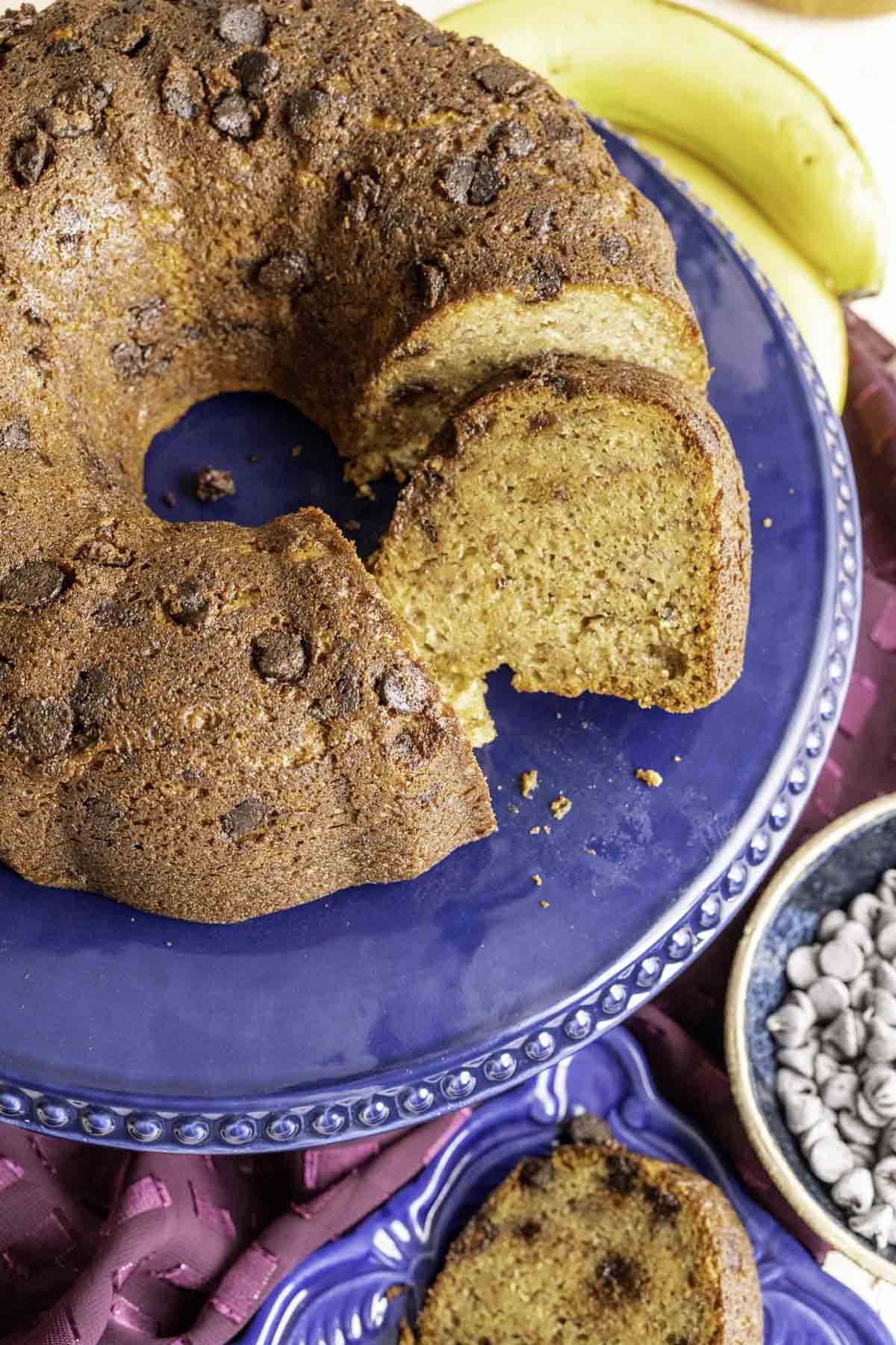 closeup of one slice of the cake on the cake plate with bananas showing in the backdrop.