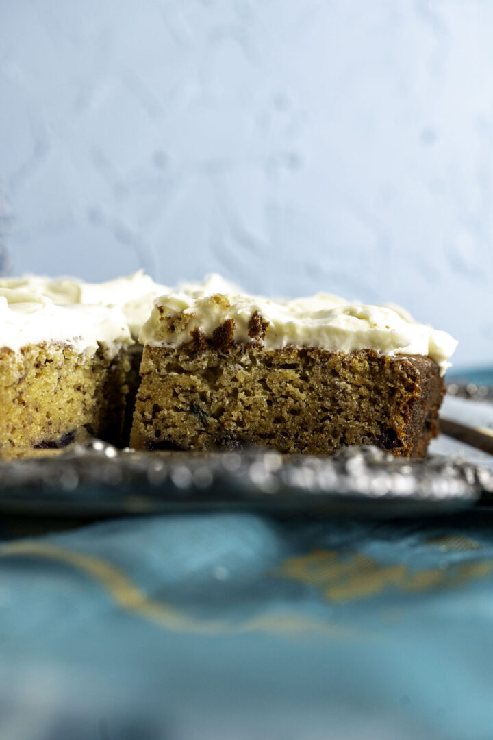 close up shot of a cake piece showing its texture and crumb placed in a tray on a blue table cloth.