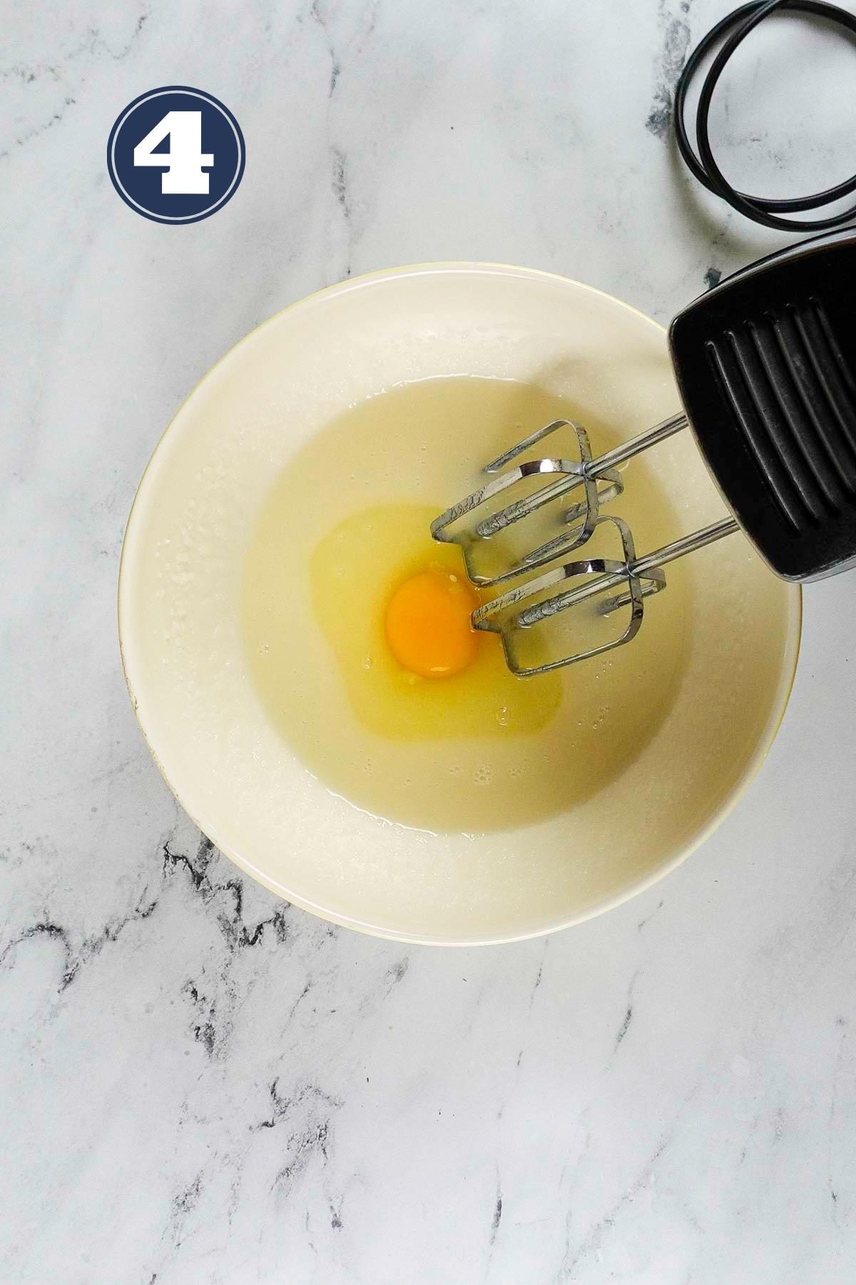 Adding eggs one by one in the beaten sugar and vegetable oil.