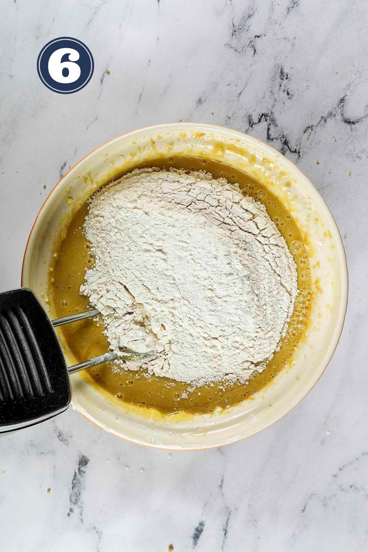 adding in the dry ingredients into the wet ingredients of the cake batter.