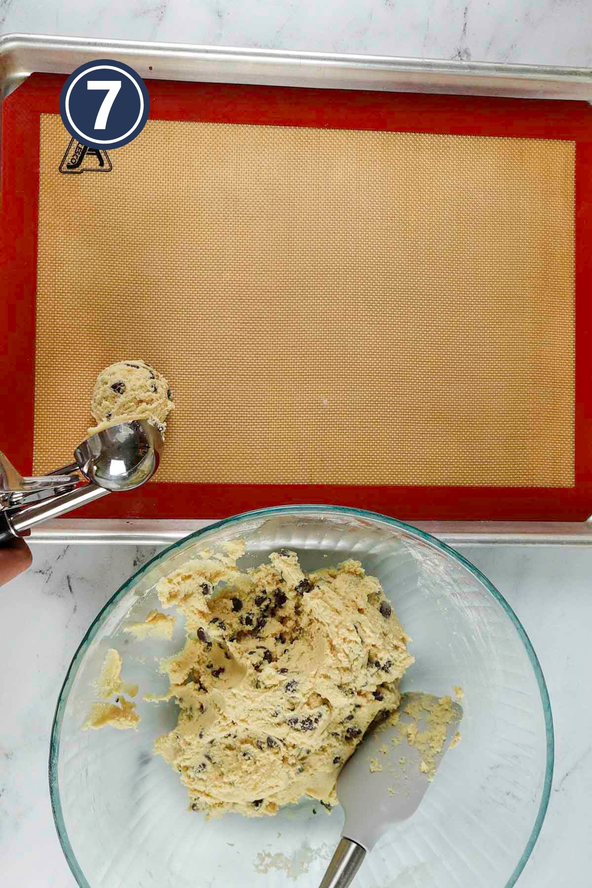 scooping out the chocolate chip cookies into the baking tray out of the batter bowl.