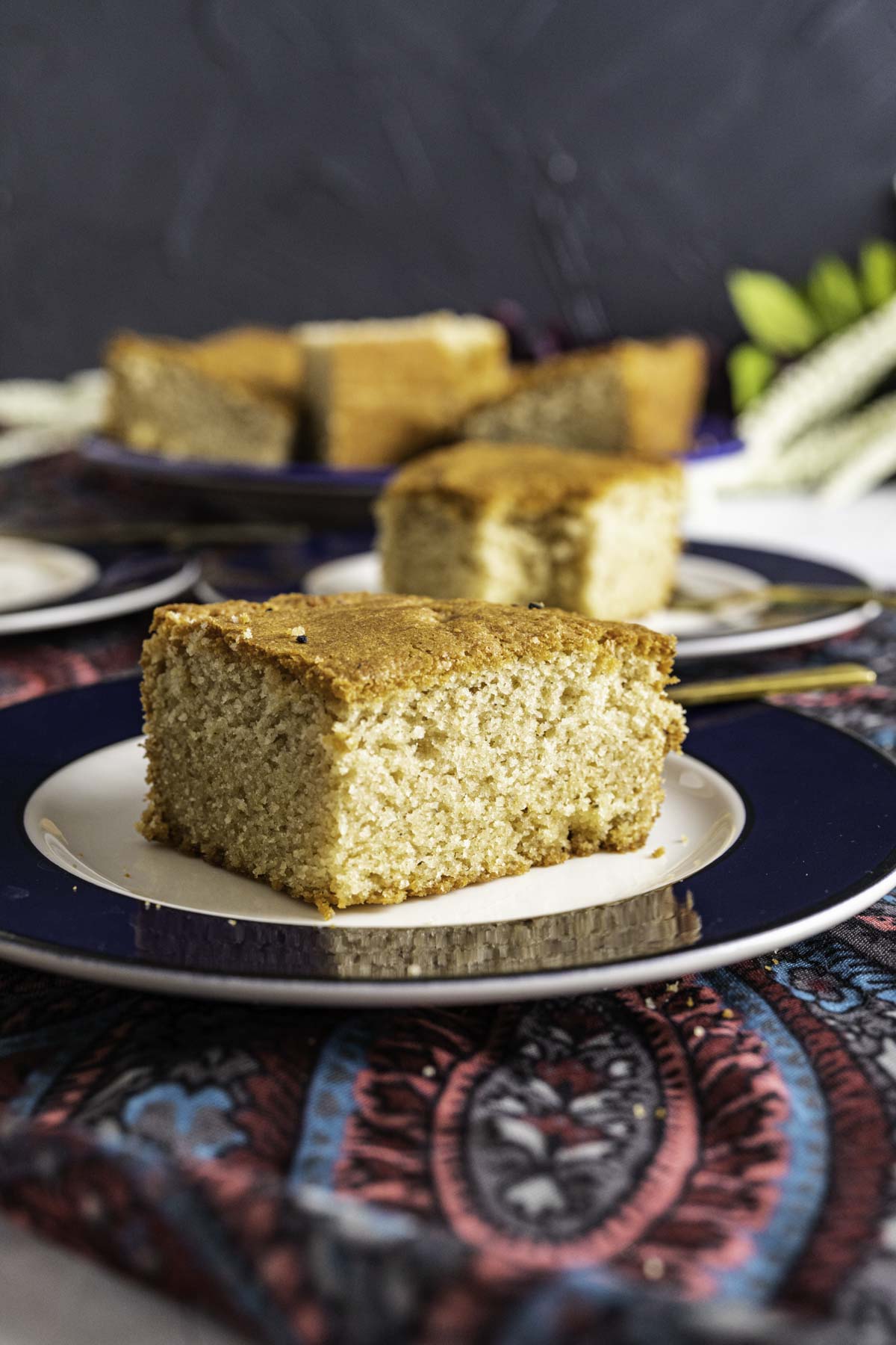 One piece of Ghee Cake sitting on a white plate with blue border.