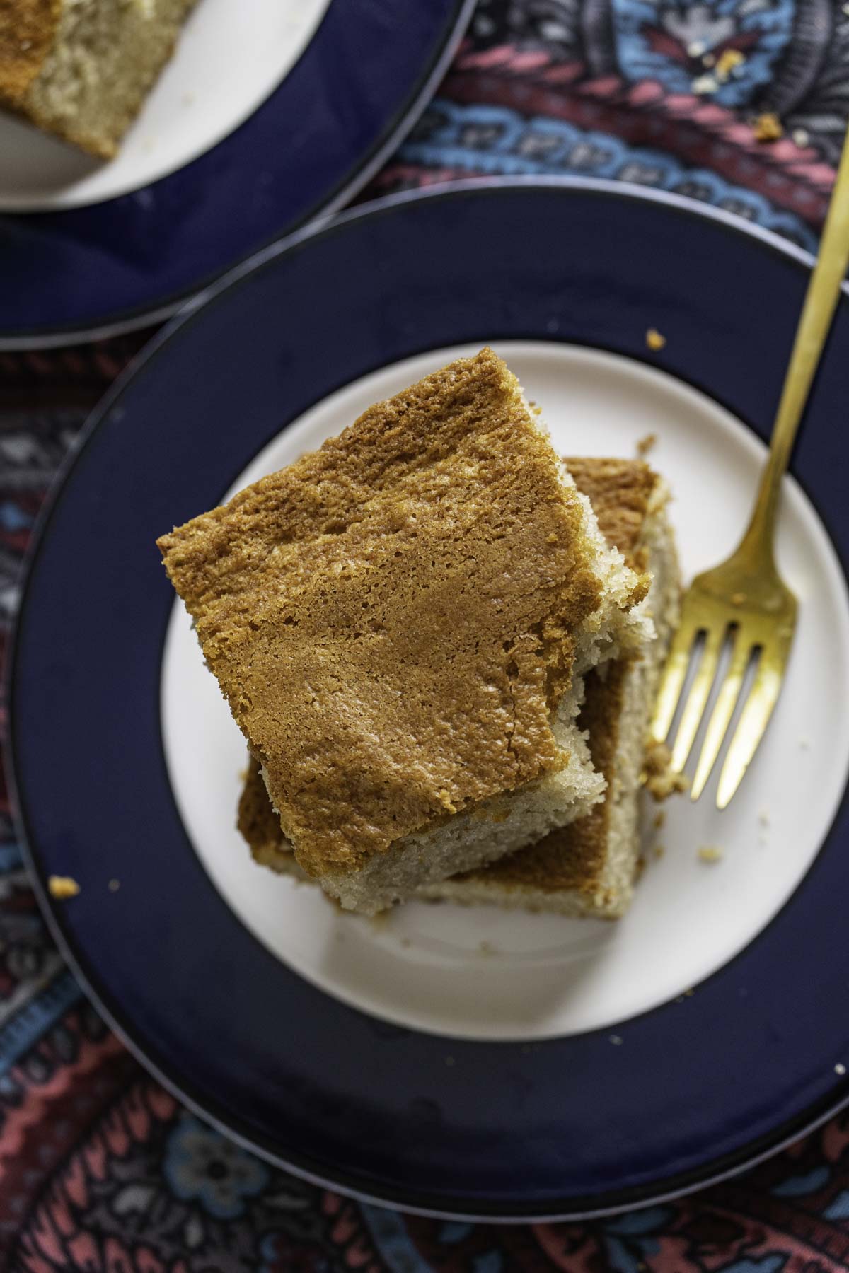 Two pieces of Ghee Cake in a white plate with a golden fork sitting on the plate.