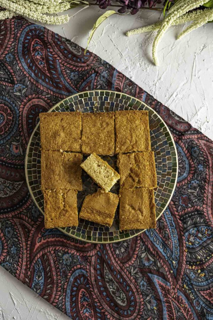 overhead shot of the desi ghee cake in a colorful multi color transparent plate.